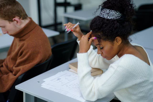 young woman studying and holding her head