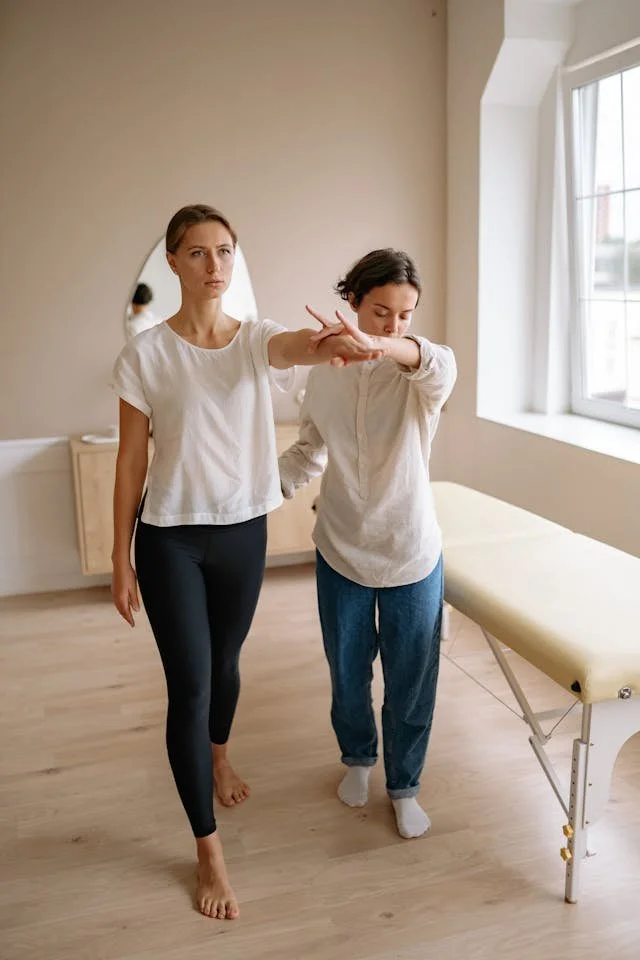 therapist assisting woman through simple movement standing next to massage table