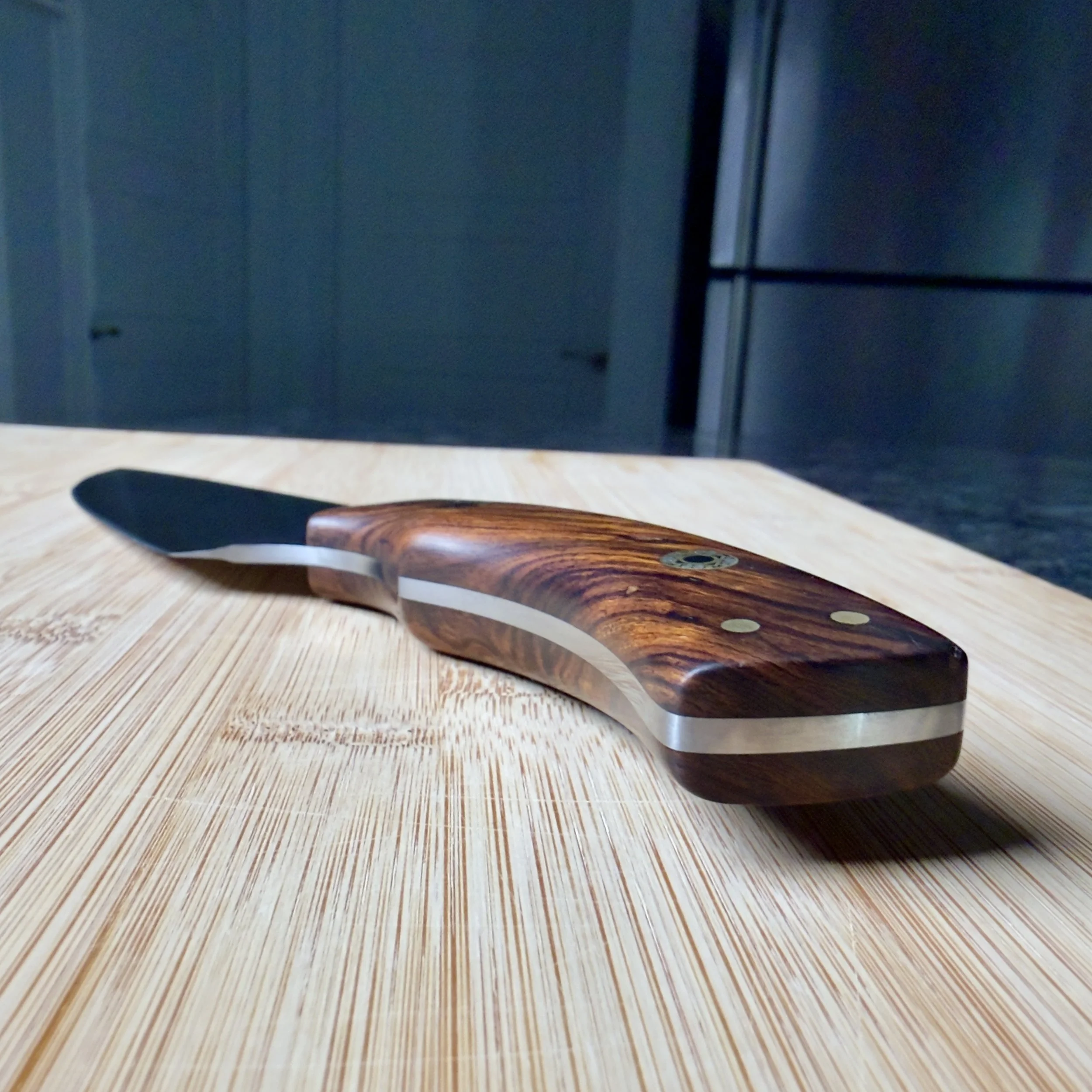 Side view of the sculpted Desert Ironwood knife handle showing full tang construction, brass pins, and decorative mosaic pins.