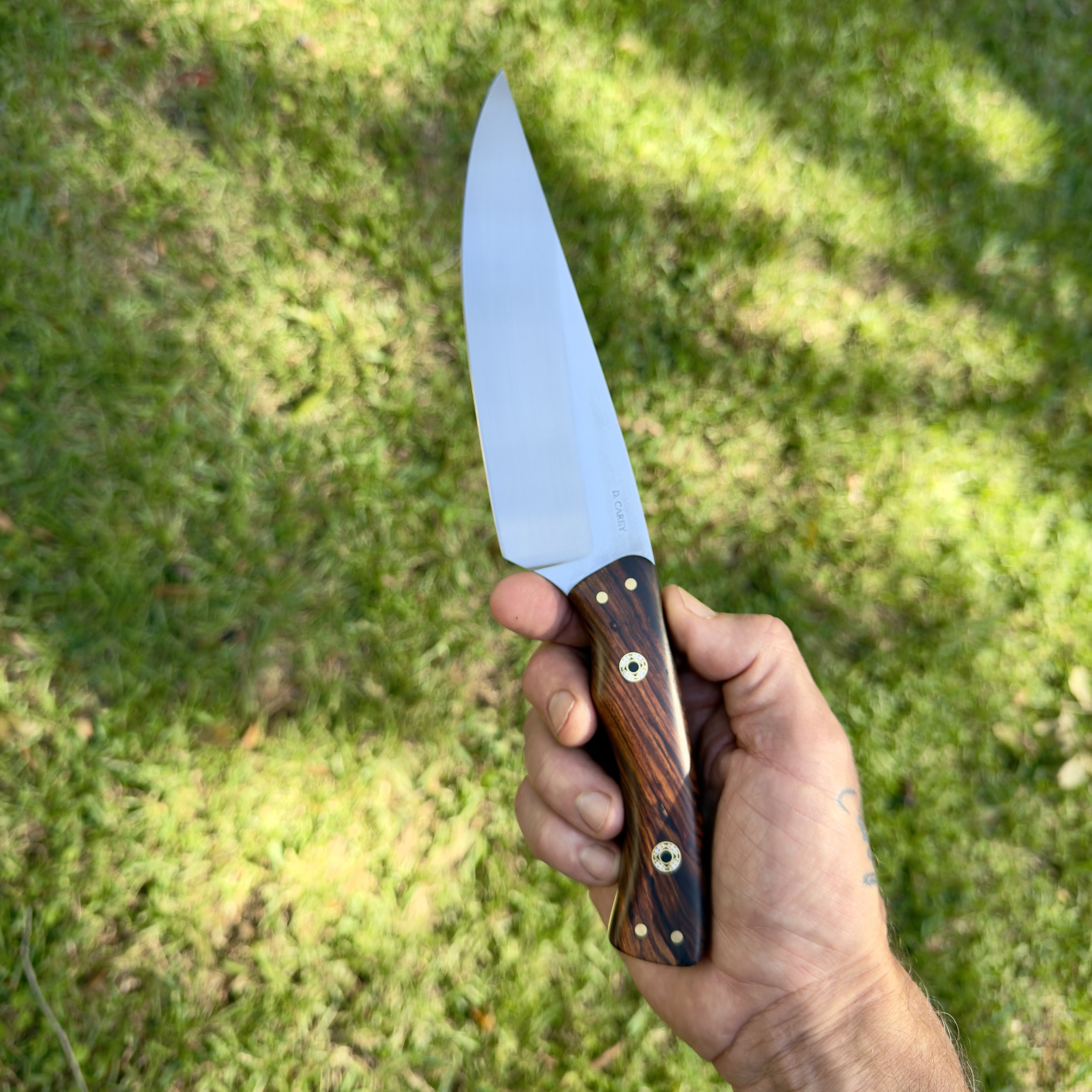 Handmade 6-inch chef knife held in hand outdoors, showing the blade proportions and natural Desert Ironwood handle.