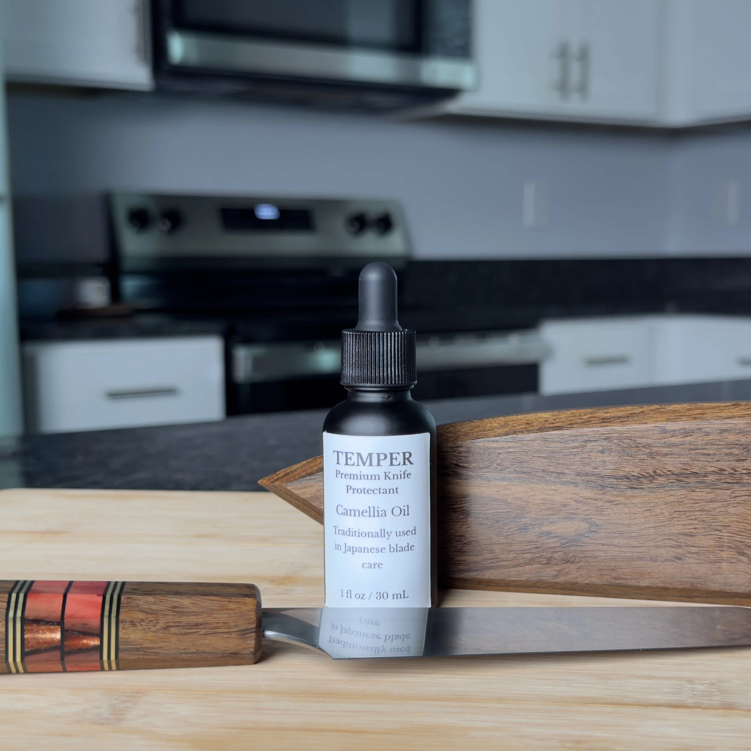 TEMPER camellia oil bottle with chef knife and wooden saya on counter