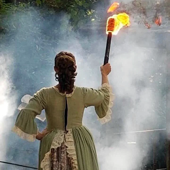 A member of the cast of Horn in the West holds the torch.