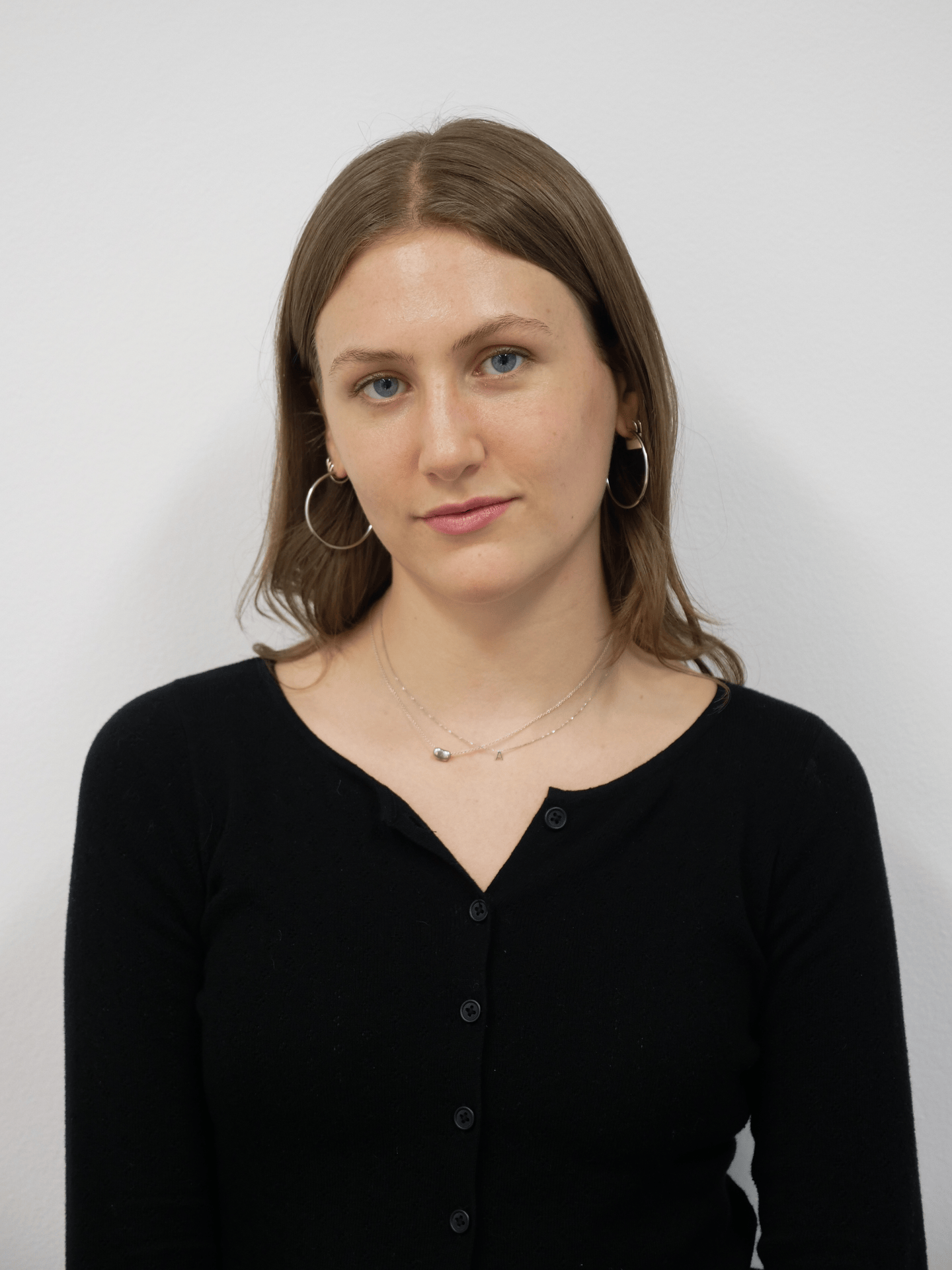 A gif cycling through several portraits of a figure. The figure has shoulder length bown hair and is wearing hoop earrings and a black cardigan.