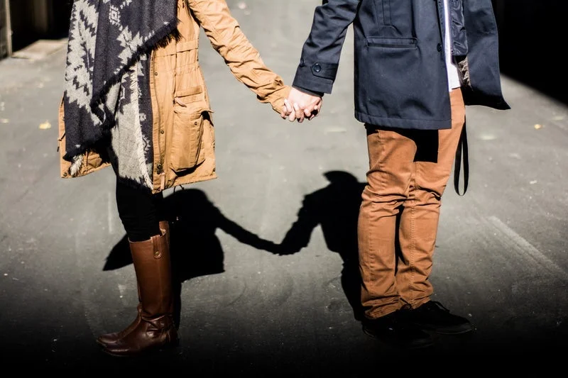 White couple holding hands but facing away from each other