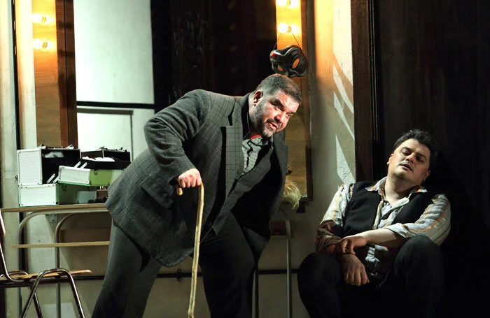 Tonio (Dimitri Platanias) leans over a walking stick as he talks to Canio (Aleksandrs Antonenko) in Pagliacci (Royal Opera House). Photograph by Catherine Ashmore.