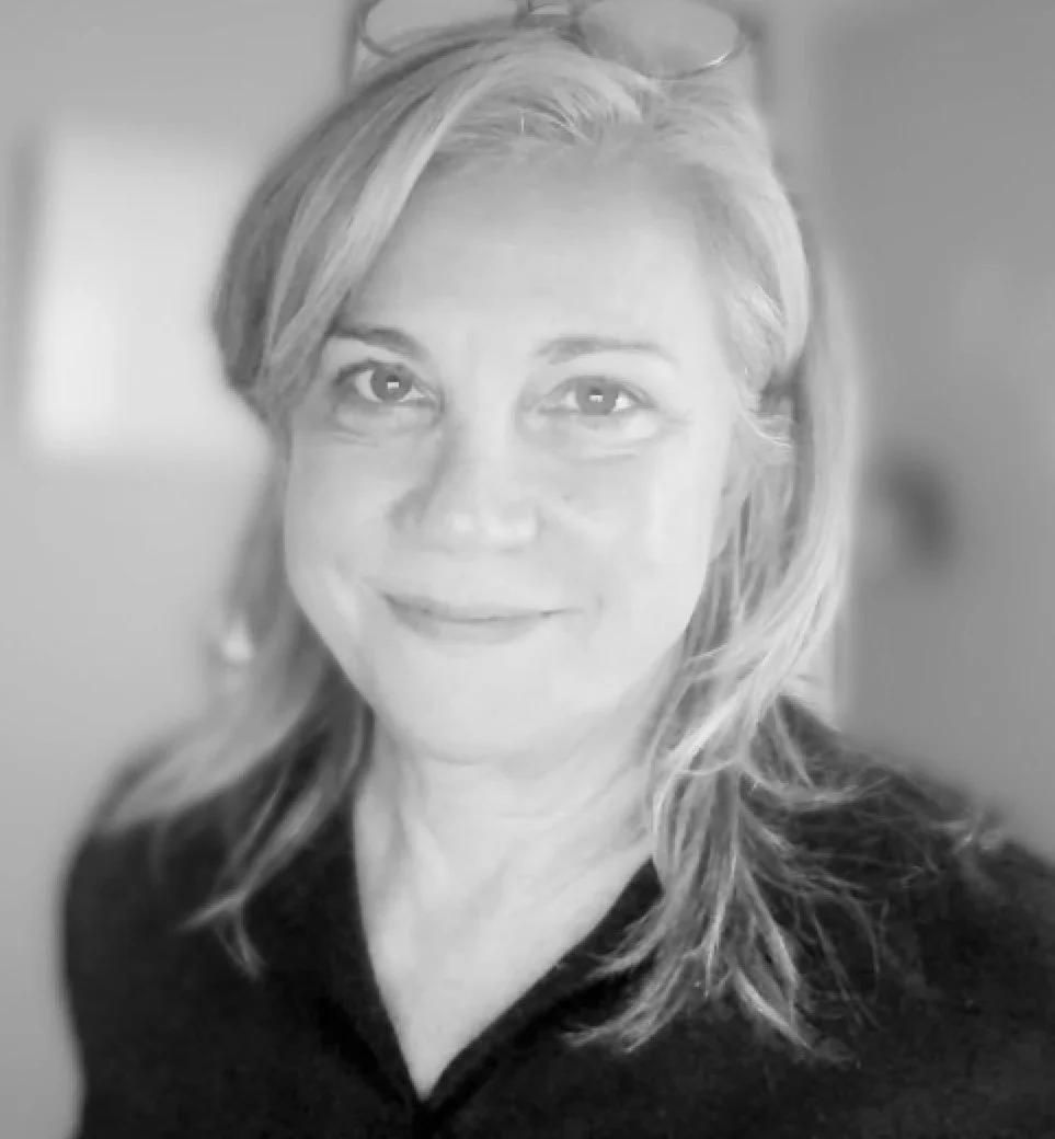 black and white image of Pamela Hastings in her home office with glasses perched on top of her head.