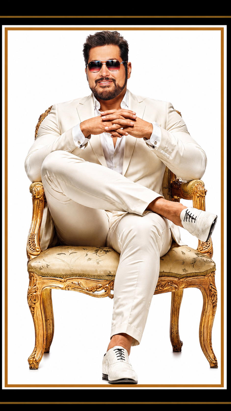 A man wearing sunglasses and a white suit sitting confidently on an ornate gold and floral upholstered chair with his legs crossed and hands clasped.