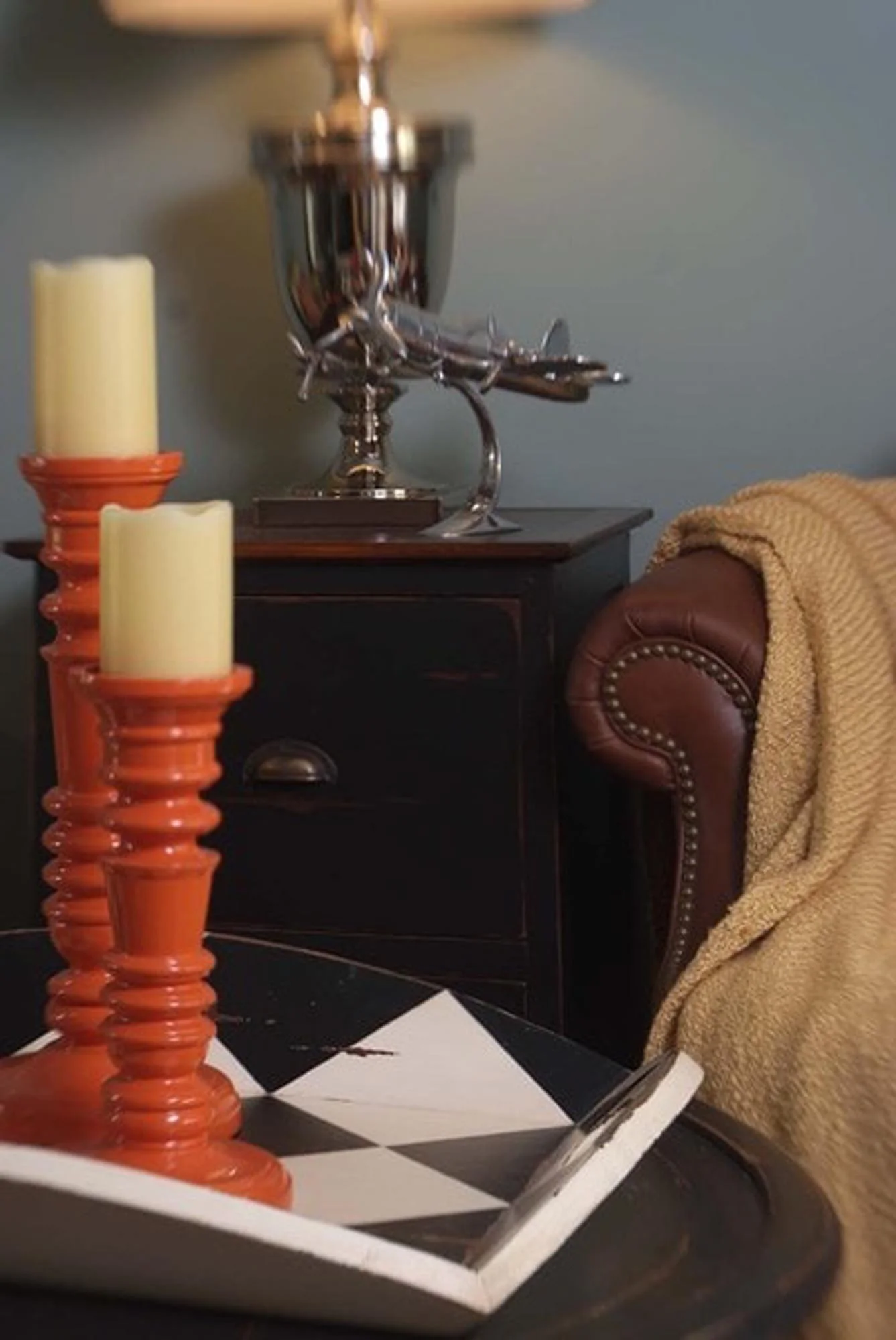 Tall orange candle stick holders with brown leather sofa in background