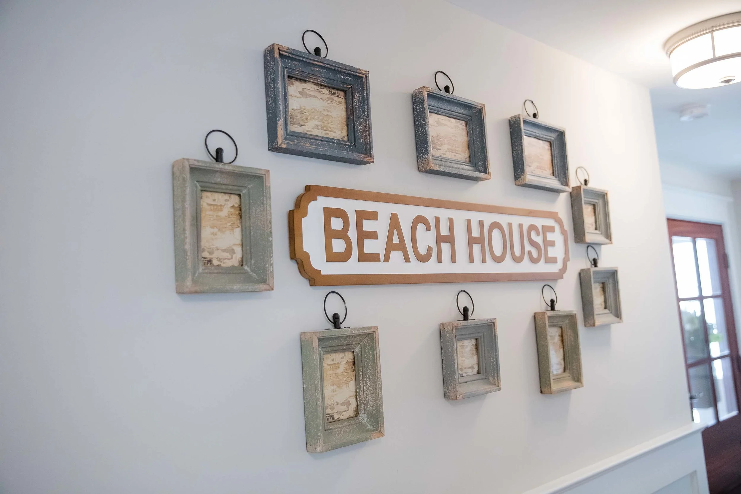 Coastal style wooden picture frames hanging on wall and wooden beach house art