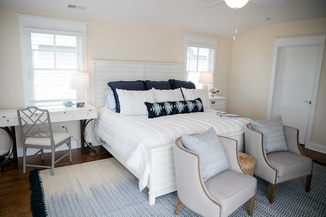 Bright bedroom with white bed and two sitting chairs