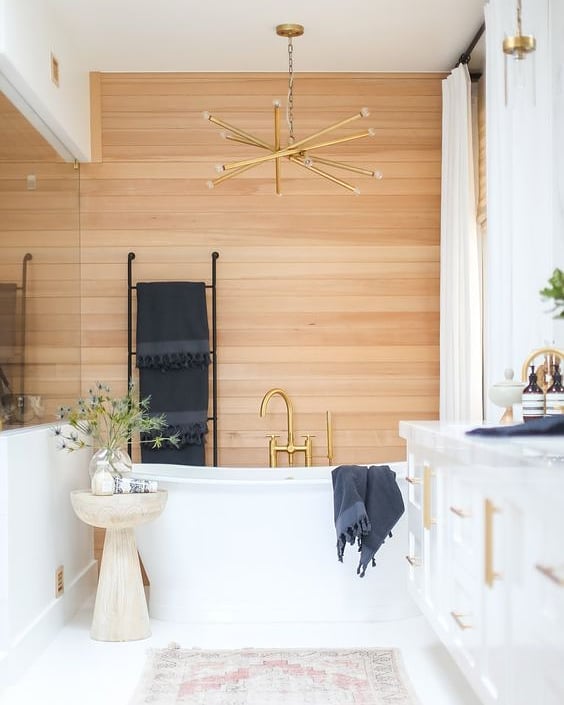 I've been seeing more and more natural, warm wood tones lately + I love the unexpected placement of it as the focal wall in this bathroom. By keeping the floors, cabinetry and ceiling a crisp white, the wood paneling warms up the space 
Design: @shop