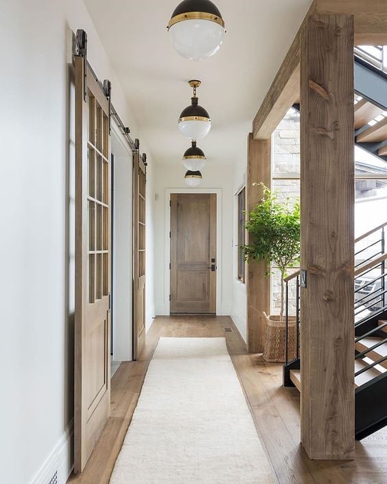 Repetition is one of my favorite ways to add architectural interest to a space.

These beautiful pendant lights draw the eye down the long hallway while adding structure to the space. 😍 But the best part may be those gorgeous sliding doors.

Design: