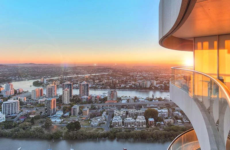 Winding river and city suburbs at sunrise, seen from a curved high-rise balcony