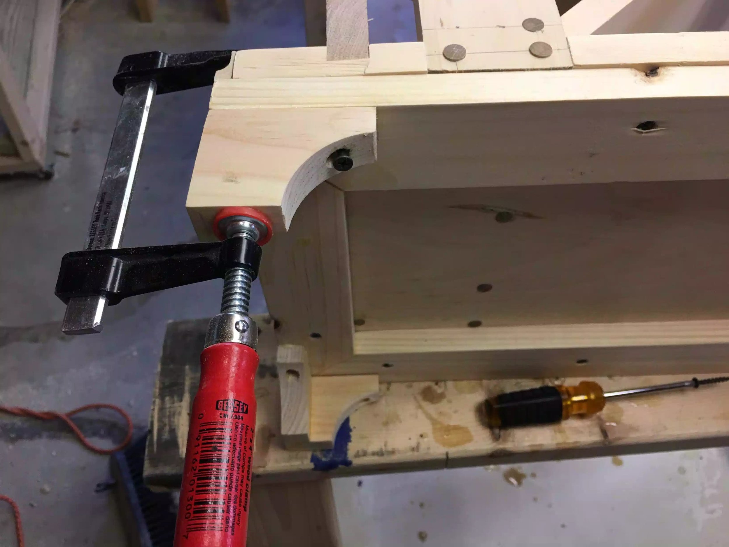 Here you can see me attching one of the feet on the frame, I used an F style clamp to keep the foot in position while I hand screw the foot on, I also added glue to the top of the foot.