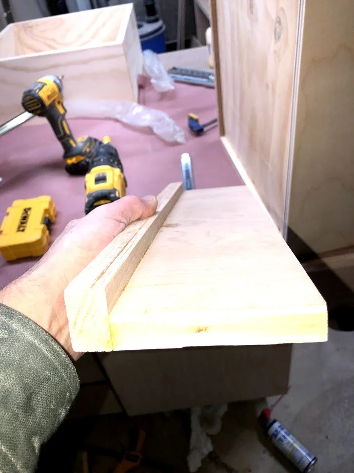 Here is a close up of the jig, its basically a scrap piece of plywood with a fence on the side that is 1-1/4” wide which when butted next to the 3/4” thick plywood gives me the required 1/2” offset to install the drawer slide.
