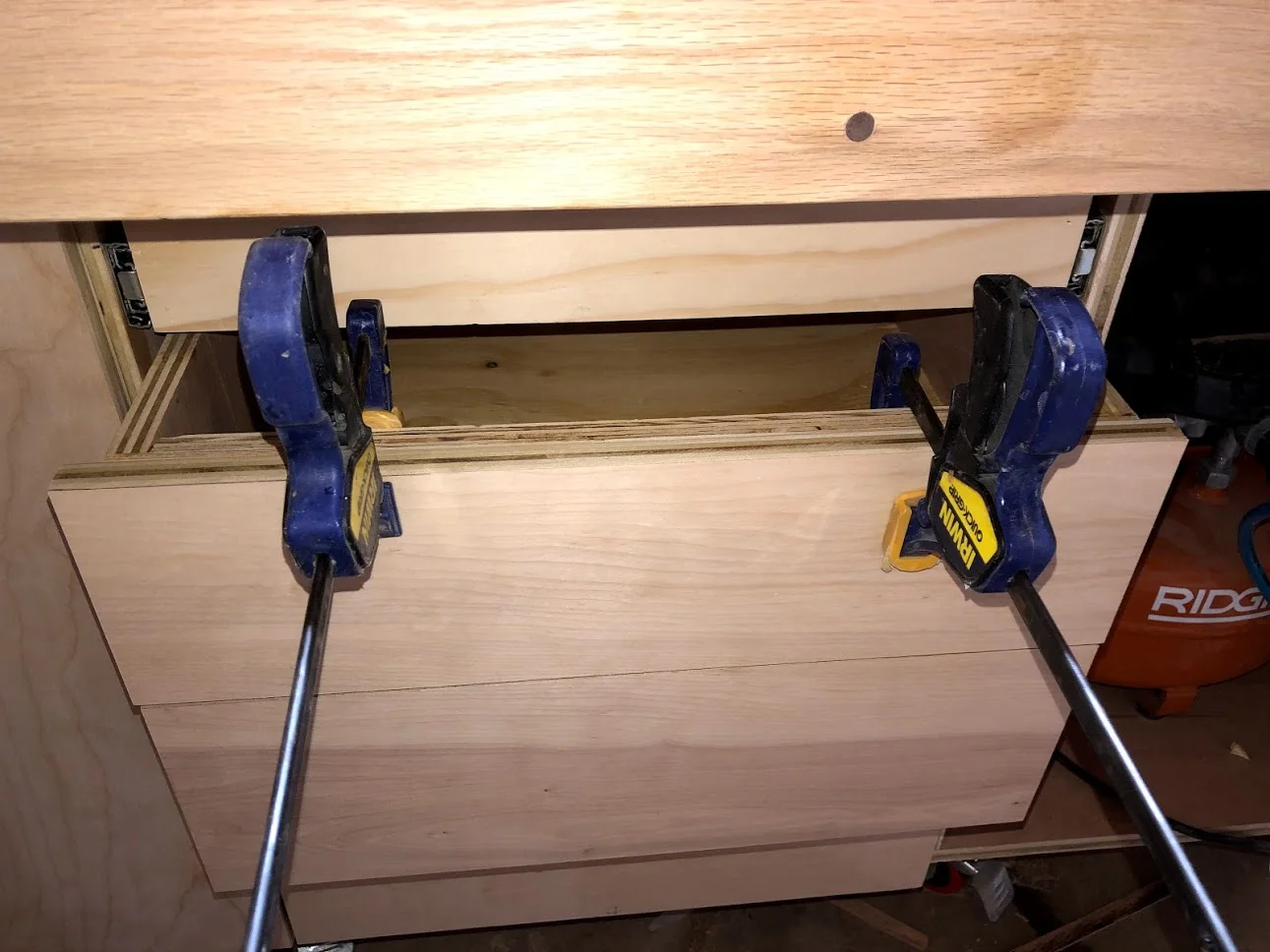 Held the false front in place with clamps while I secured brad nails from inside the drawer, after that I secured permanently with screws