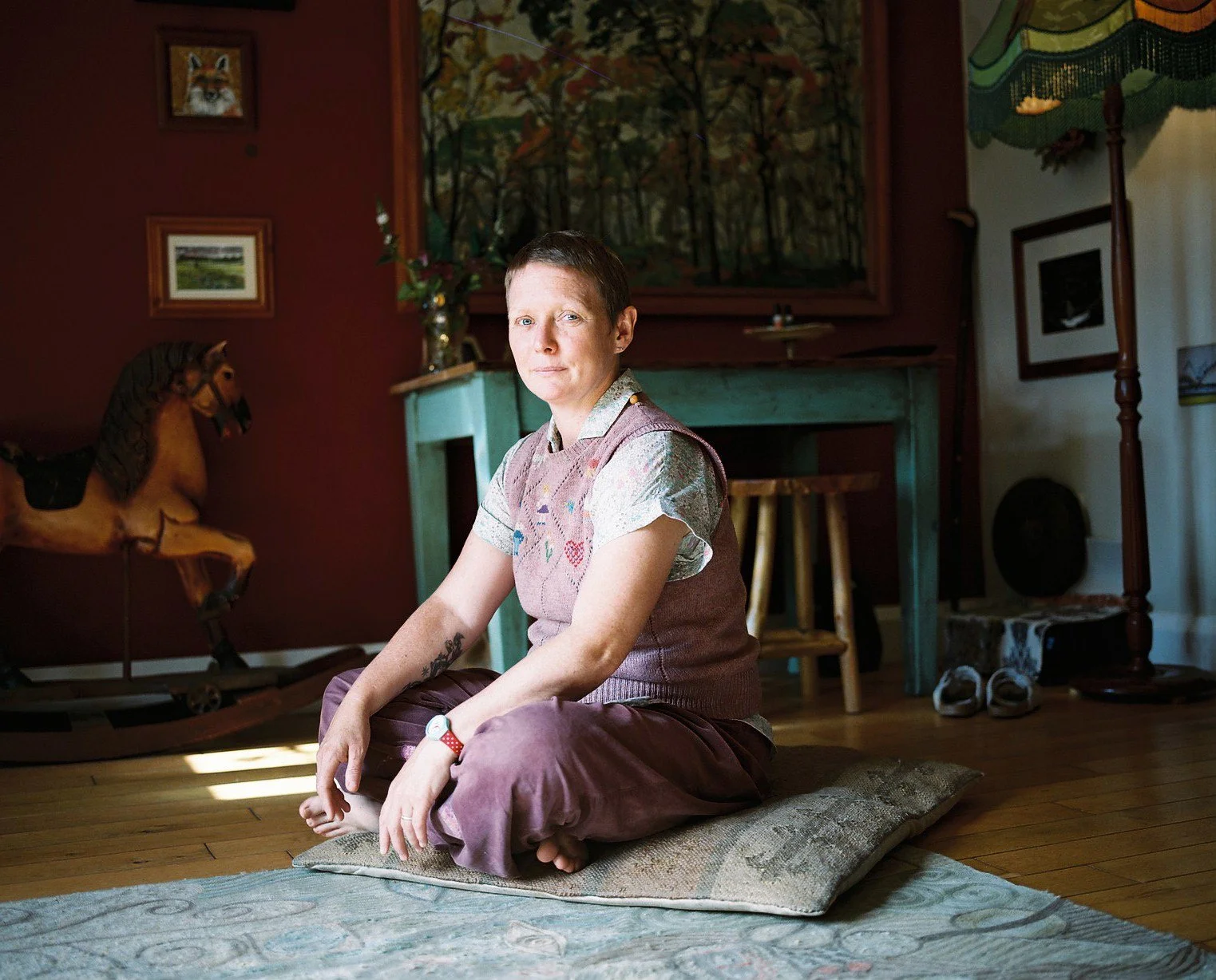Woman sitting cross-legged on a floor cushion, looking to camera.