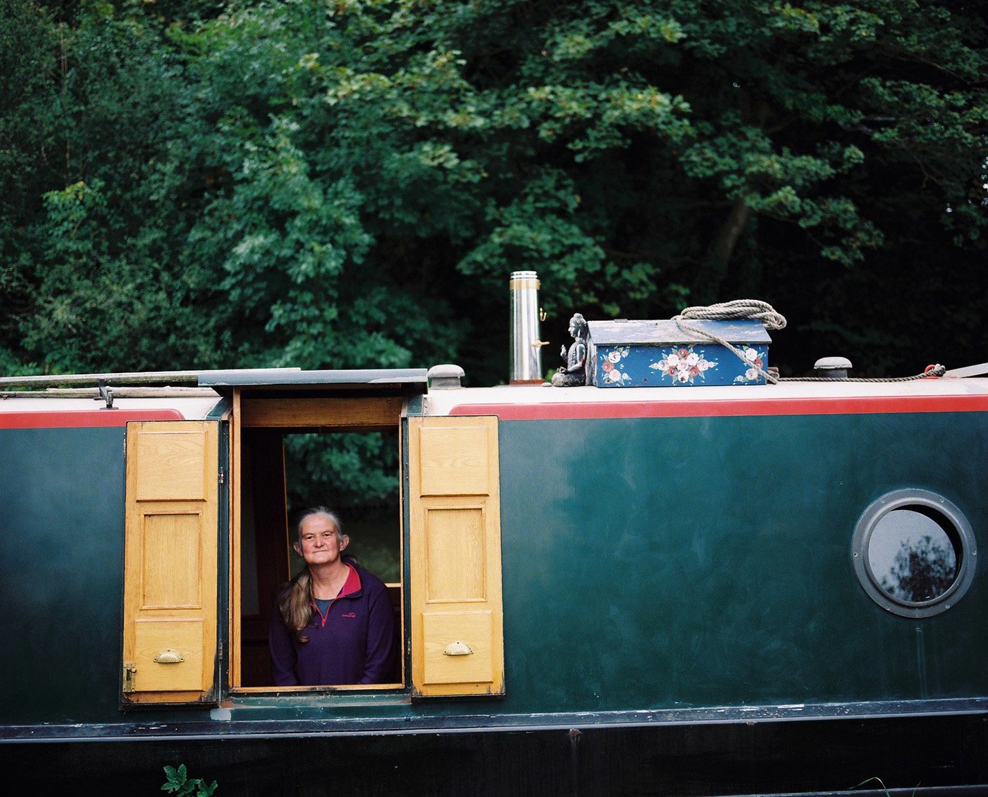 Woman looking out of the windows of a canal barge.