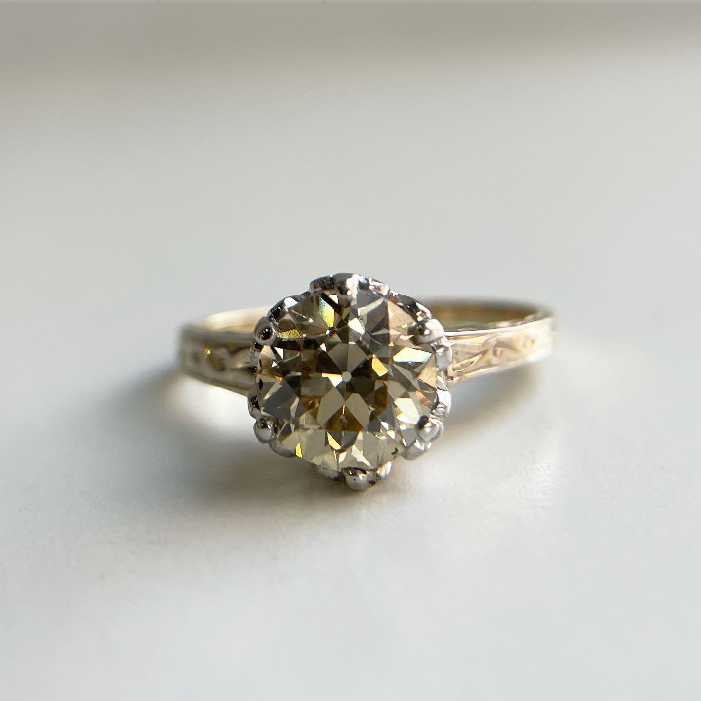 This antique Art Deco diamond solitaire engagement ring showcases a 1.63 carat old European brilliant diamond at its center. The ring is crafted from 14k yellow gold, and platinum, weighing 2.9 grams. The center diamond has a clarity grade of VS1 and