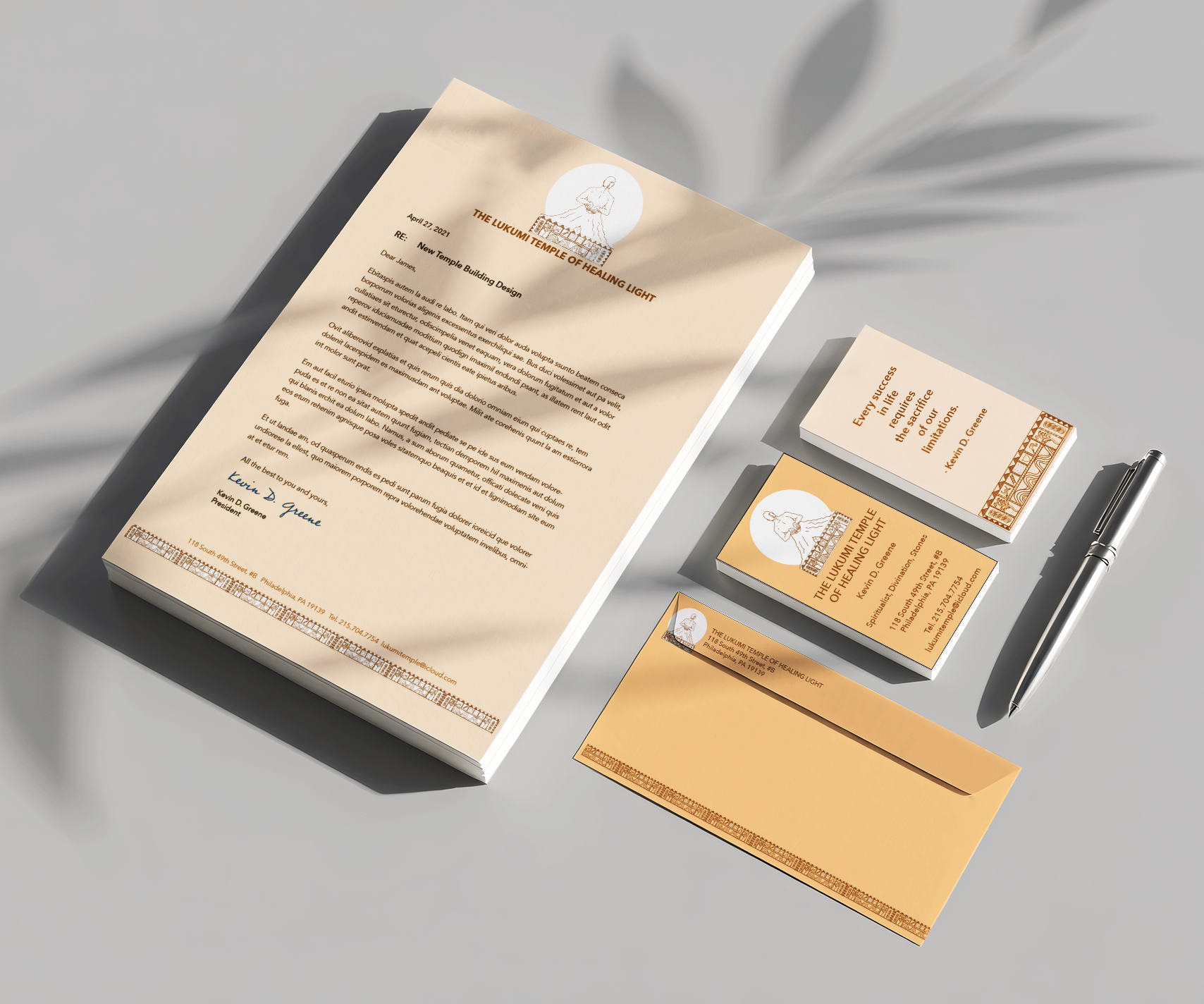 Set of printed materials including a letter, business cards, and an envelope for The Lukumi Temple of Healing Light, featuring a logo of a person meditating or praying with a scenic background, in shades of beige, white, and brown, along with a silver pen on a light gray surface.