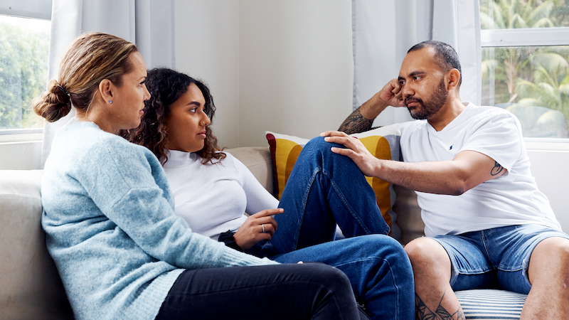 A family of three sitting on a couch to talk