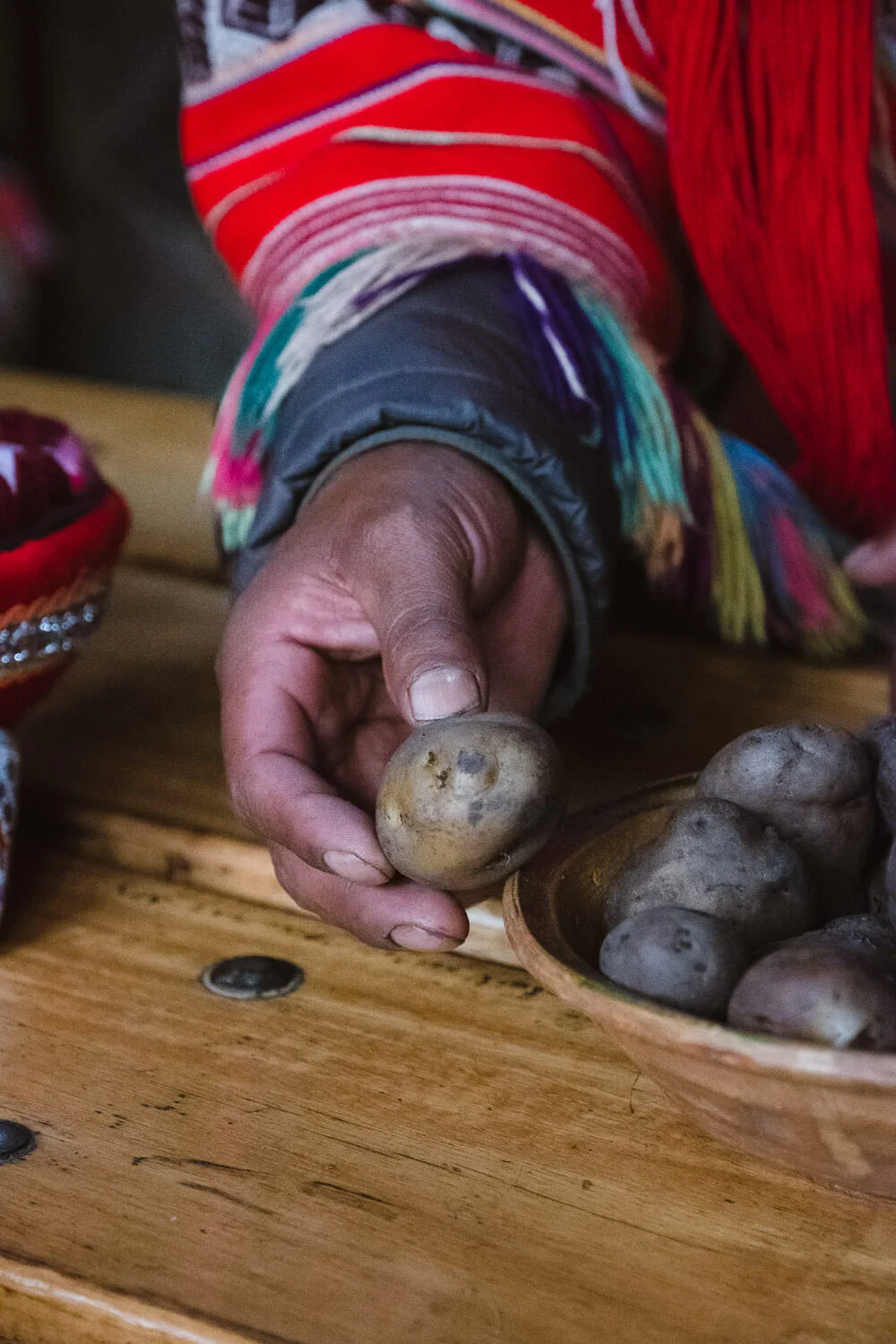 Snacking on potatoes inside the home of one of the weavers of Patacancha, The Sacred Valley, Peru. Travel photography and guide by © Natasha Lequepeys for "And Then I Met Yoko". #peru #sacredvalley #patacancha #photoblog #travelblog #travelphotography #portraitphotography #travelitinerary #fujifilm #weaving #tradition #culture #people #andes #village #weavingdemonstration #cusco #ollantaytambo #travel #travelperu