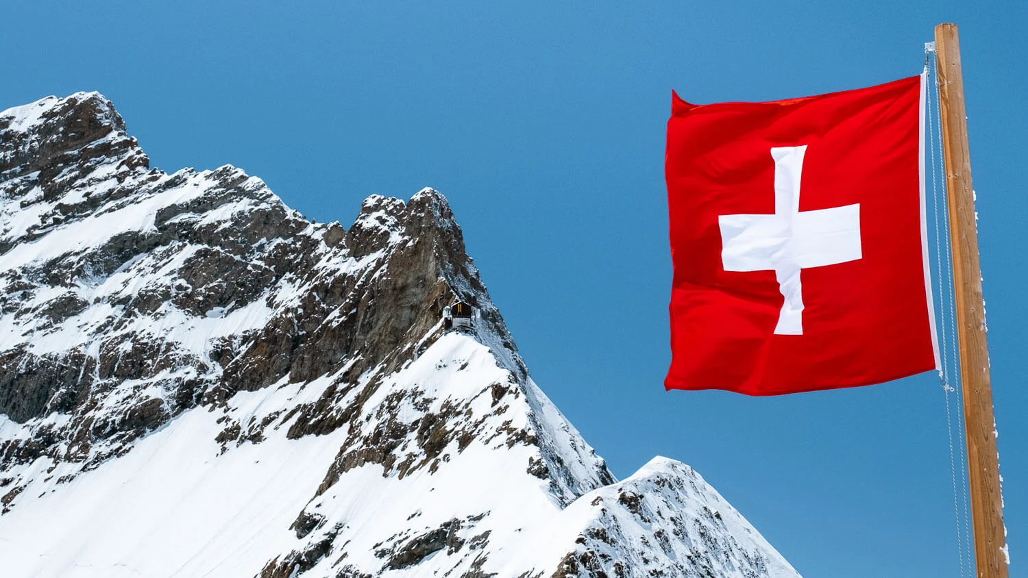 The Swiss flag and mountain peaks Jungfraujoch, Switzerland. Travel photography and guide by © Natasha Lequepeys for "And Then I Met Yoko". #wengen #jungfraujoch #travelguide #switzerland #travelphotography