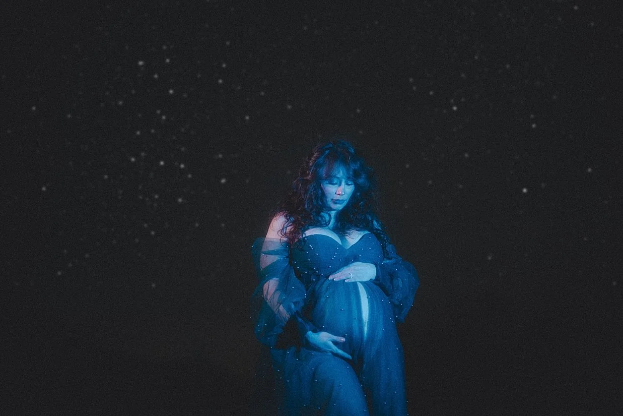 Artistic maternity portrait blending the night sky with fantasy-inspired elements.