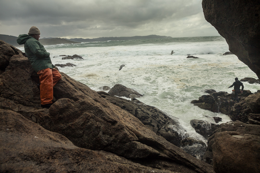 December 16, 2011 - Laxe (La Coruña). "Feuto" - a retired percebeiros - observes his son finding his way on the cliff. He can't stay home when the sea is in bad conditions and he stays all the time with his son. © Thomas Cristofoletti 2011