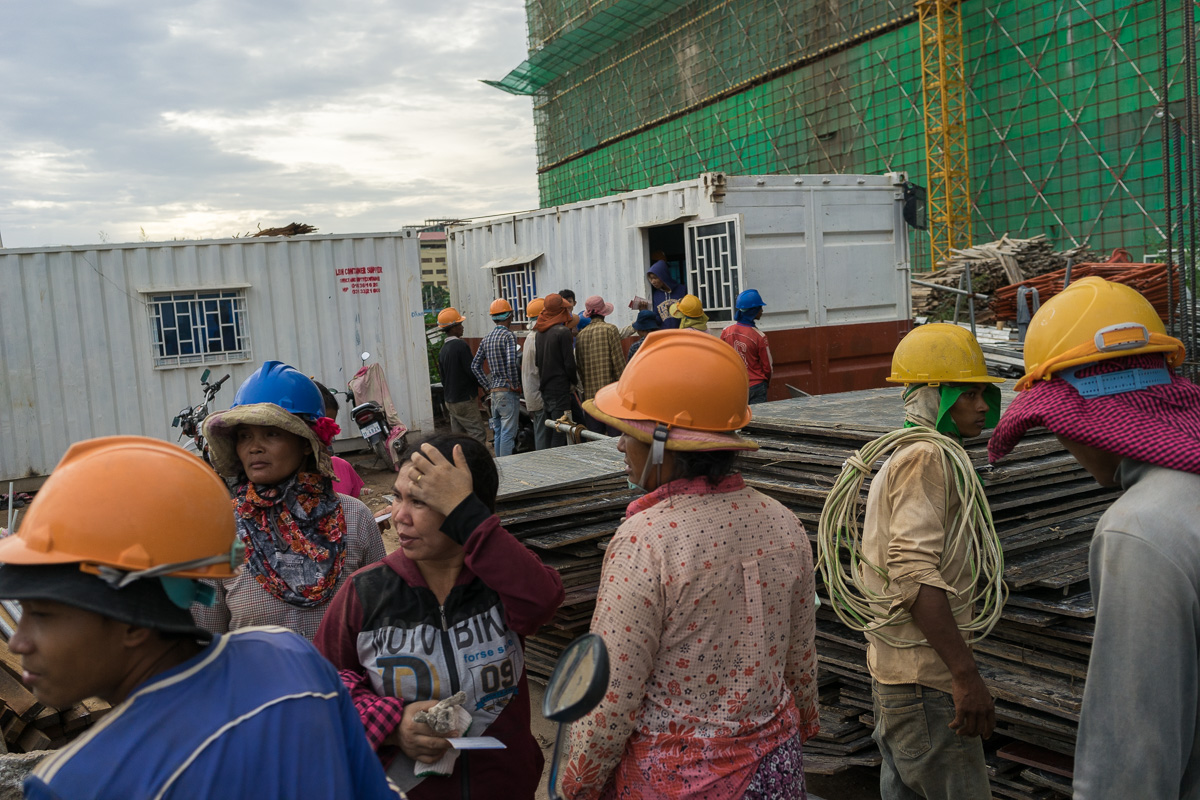 August 11 - 2016 - Phnom Penh (Cambodia). Construction workers wait in line to be paid after a day of work in a construction site in Phnom Penh. Cambodia has undergone rapid economic development in recent decades. However, the country still lacks the infrastructure required for the energy sector to match the pace of development and the capital Phnom Penh consumes 90% of Cambodia’s electricity. © Thomas Cristofoletti / Ruom