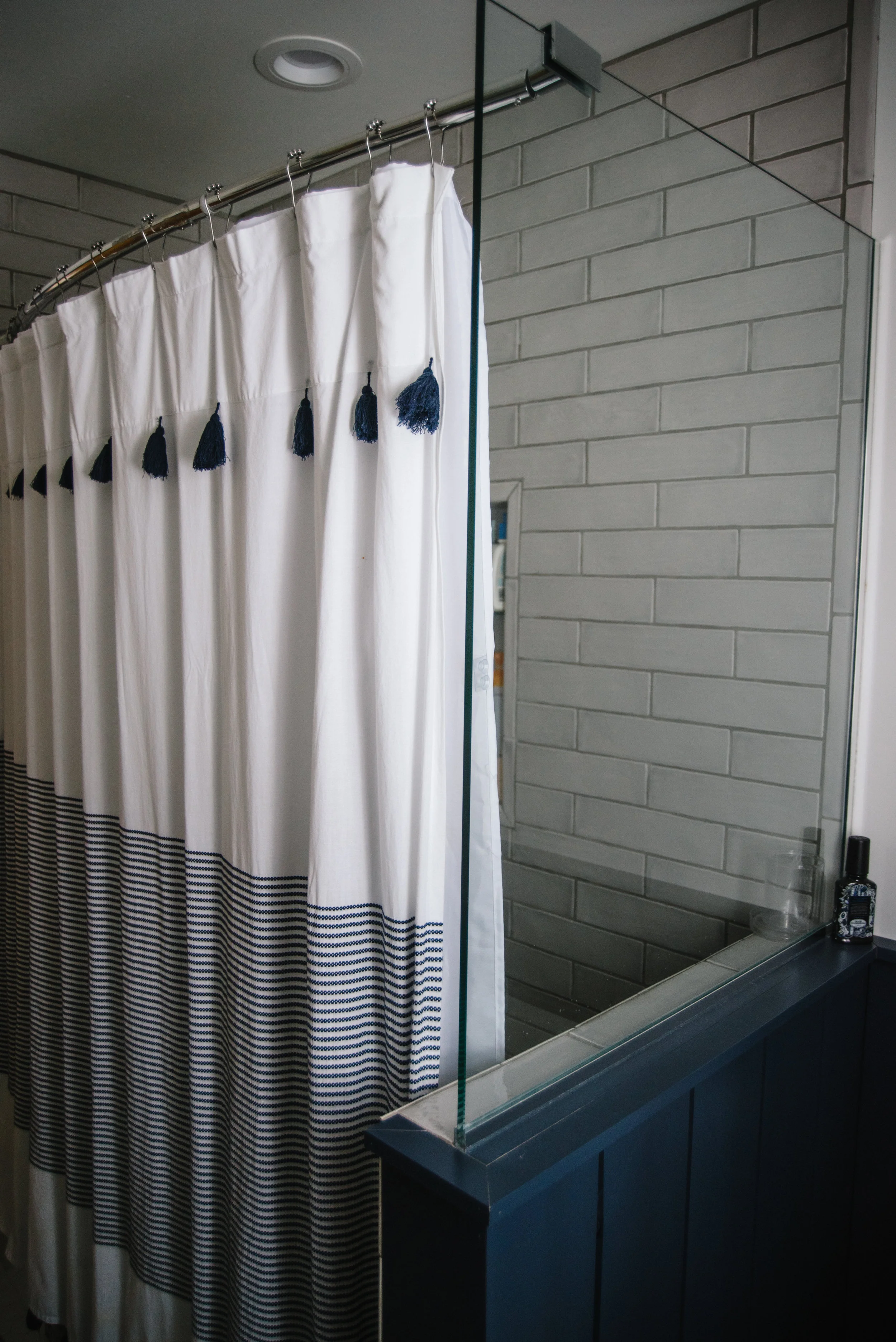 Newly renovated bath/shower with tempered glass wall.. Shower curtain by Peri Home, bloomingdales . 3x12 Retro Perla gray Tile via the Tile shop . Photo via Rachel Cuthbert Photography