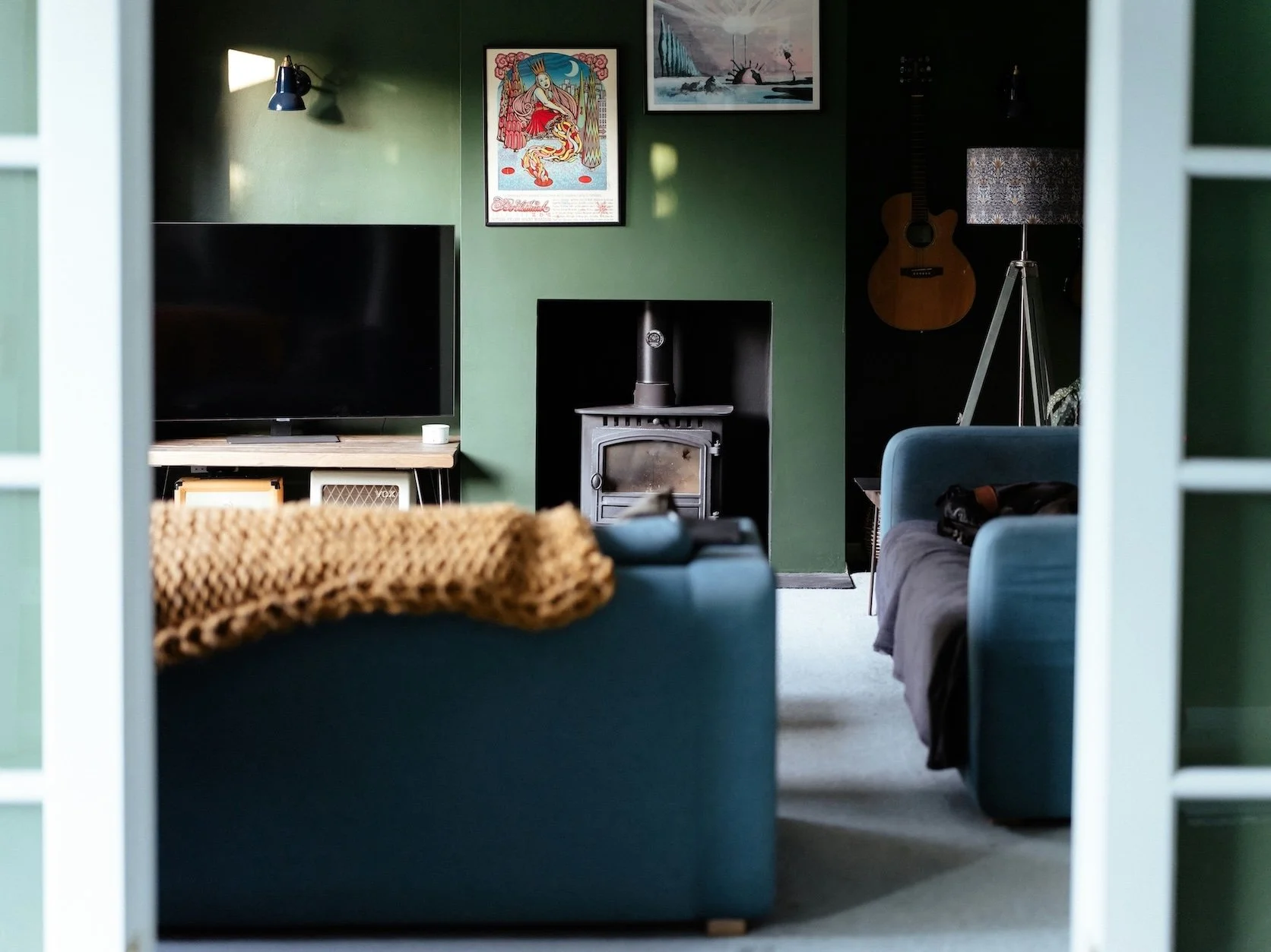 Blue sofa against green walls with art and decor in organized Portland living room.