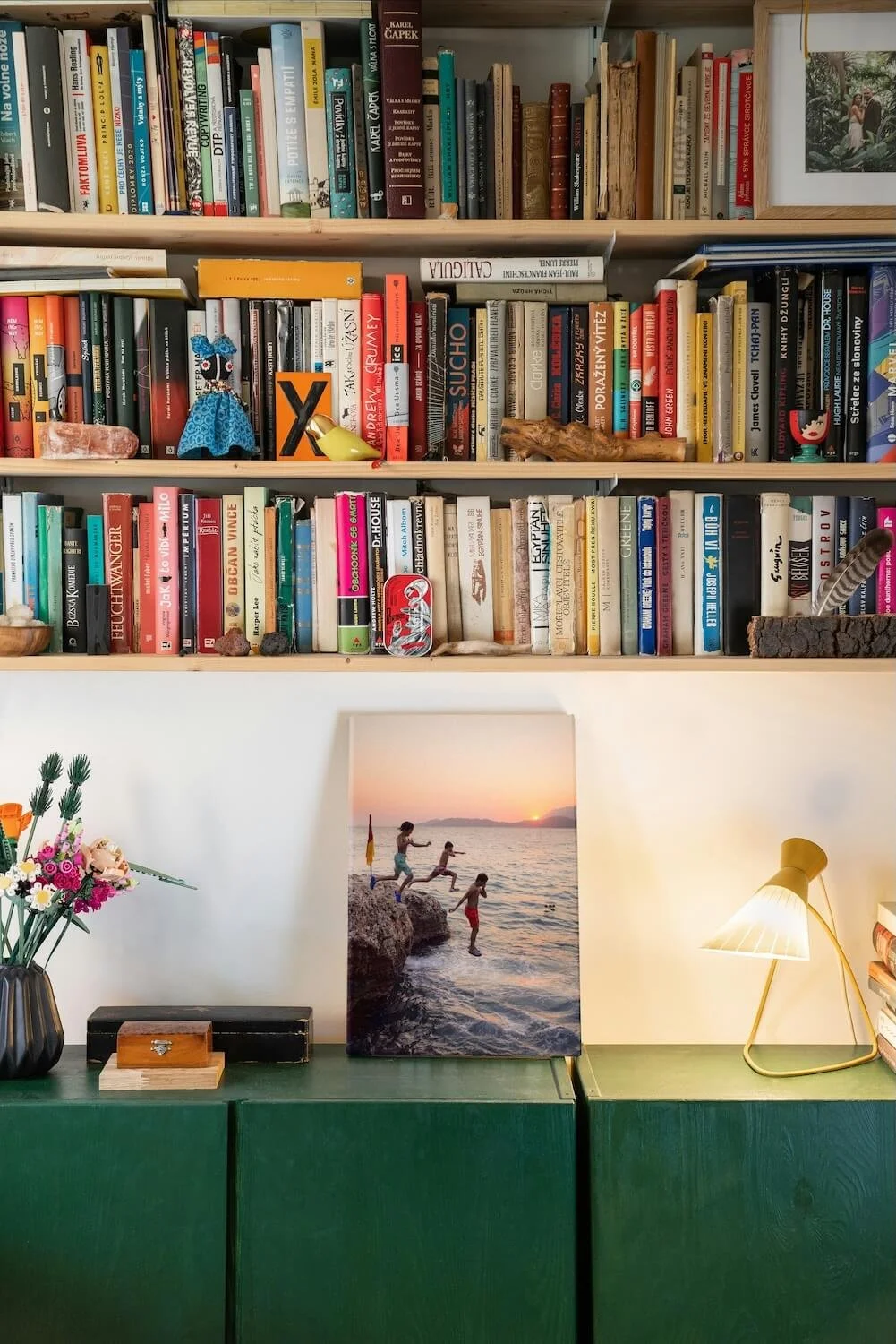 Wall-mounted bookshelves with personal decor and a green console, creating a thoughtfully styled, organized space.
