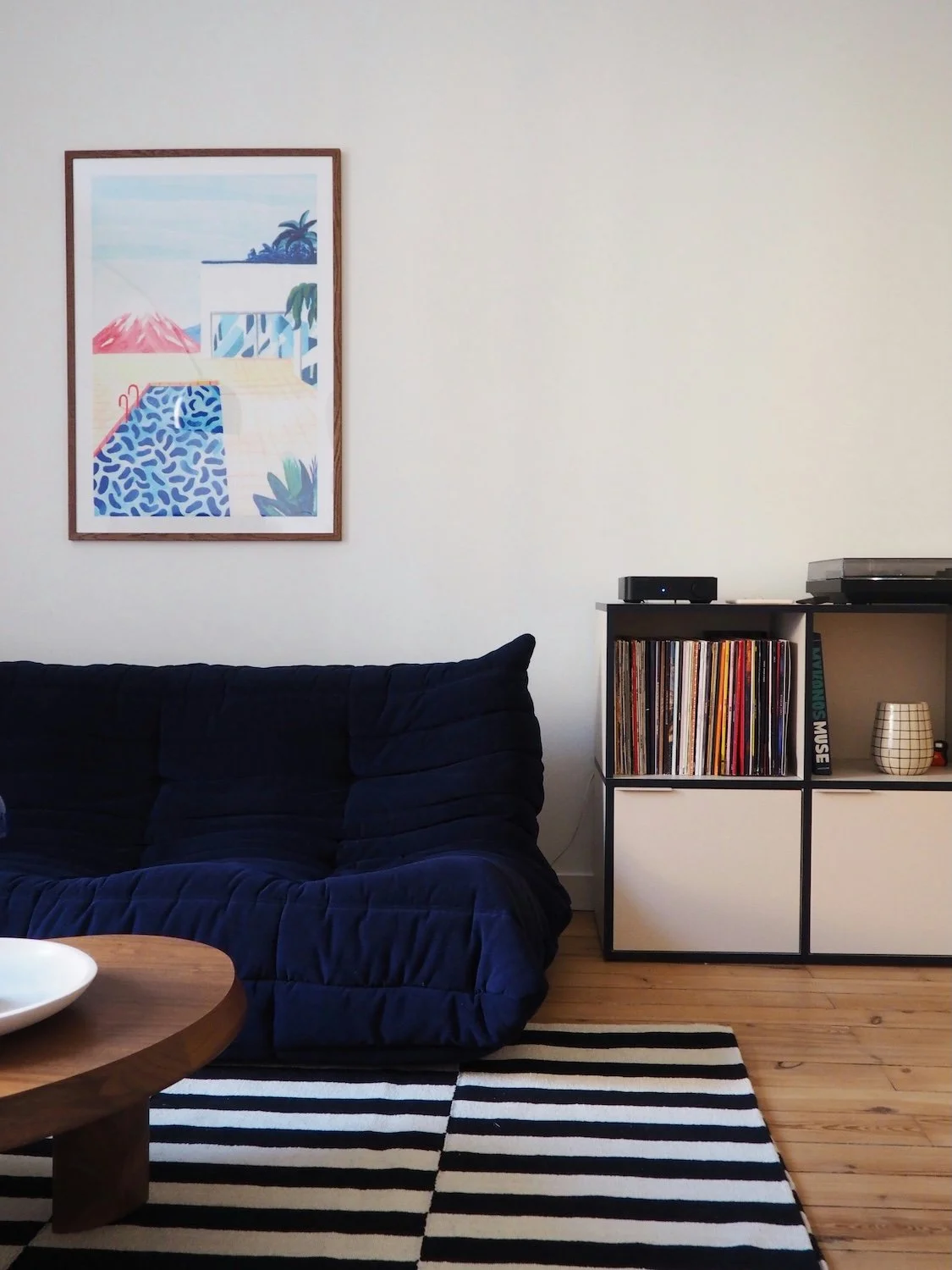Organized living room with a blue couch and record shelf after decluttering and home organizing.