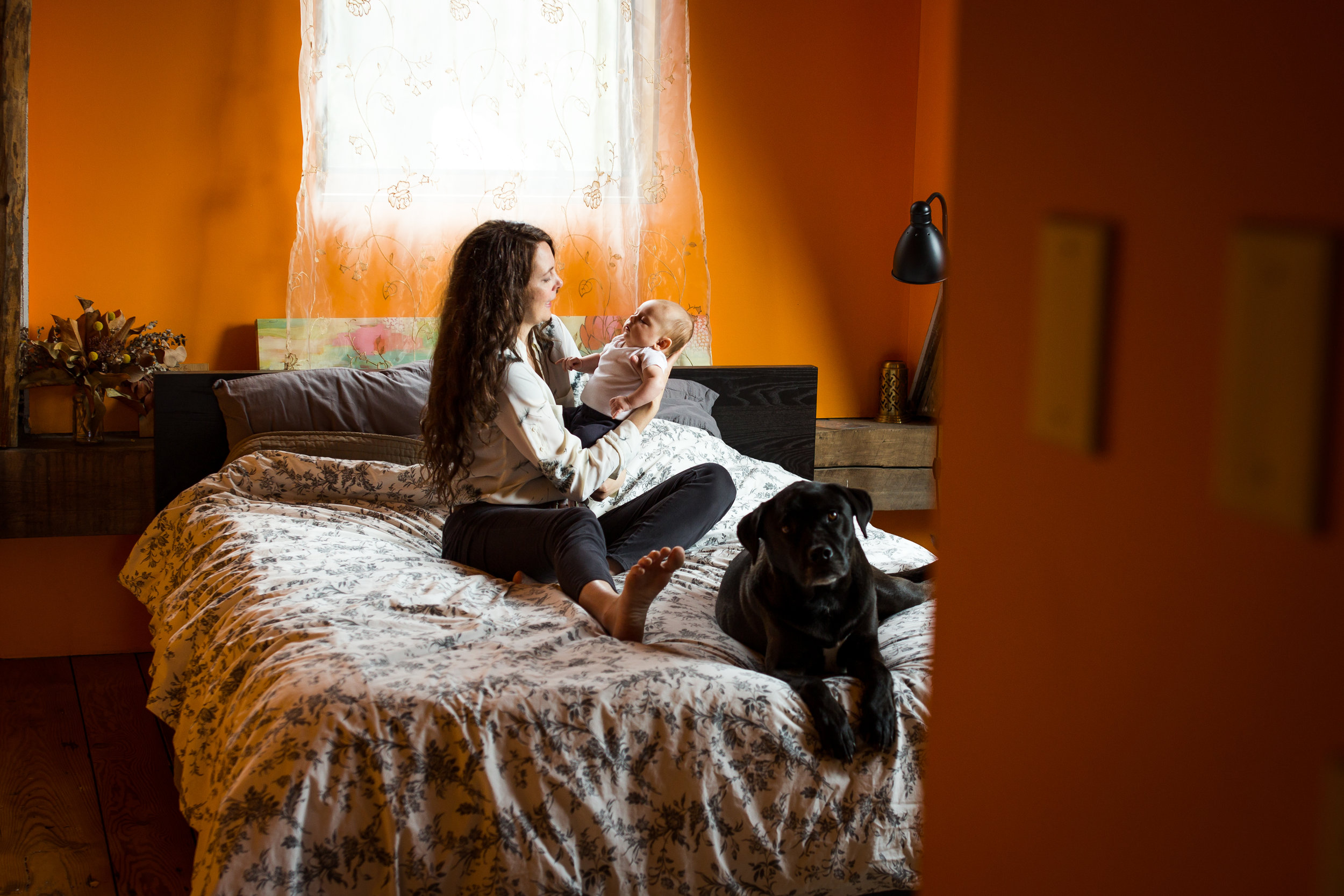 Mom holding newborn with dog on bed | Jaime Bugbee Photography
