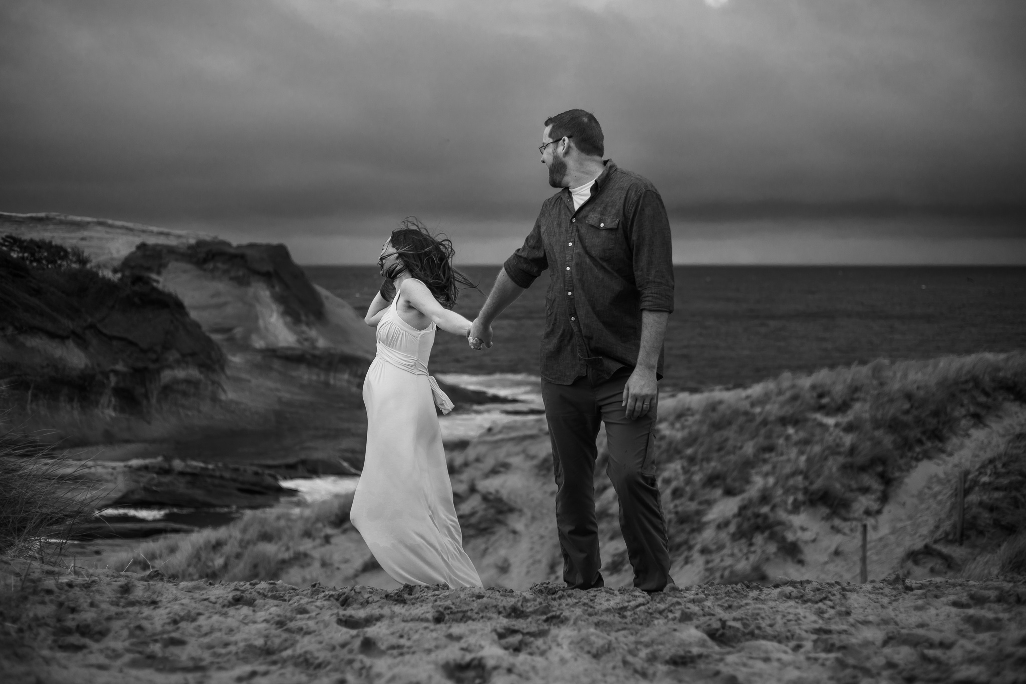 When is the best time for maternity photos blog features a moody black and white dramatic image of expecting couples on the sand dunes at the coast. 