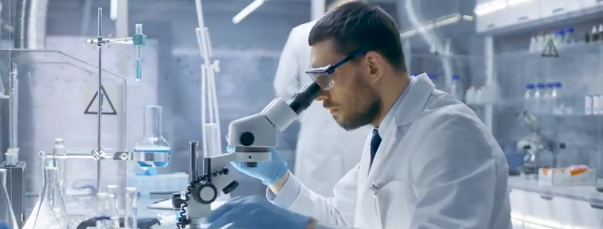 man looks at microscope.png