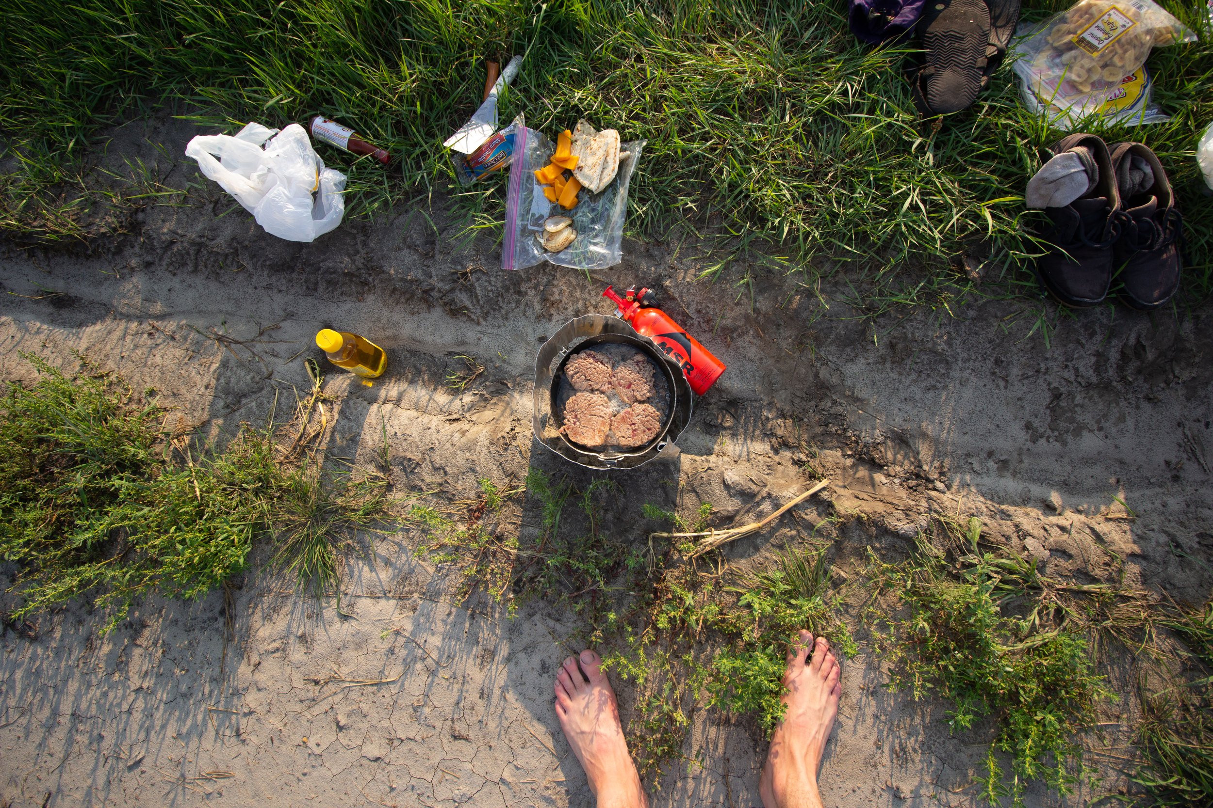 Cooking dinner on a small portable stove after a long day of riding with barefeet.