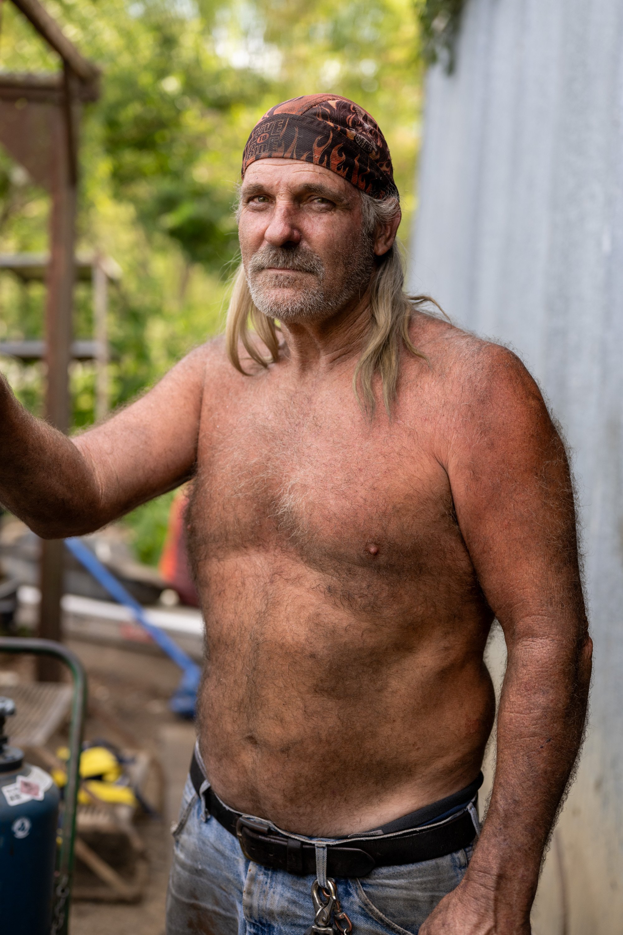 Al Switzer, 57, takes a break from working on his truck outside his garage off Martin Road near Renaker, Kentucky, on Sunday, August 11, 2024. Part of Boyd's Station Project 306.36 on rural America