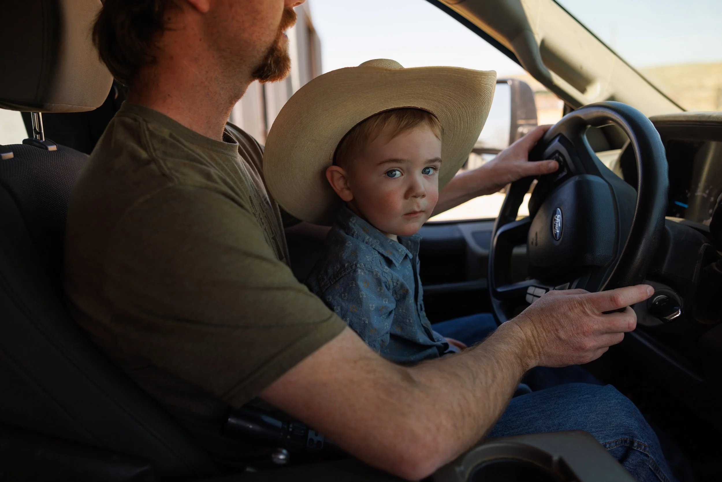 Kendall Koss, 26, and his son Kelly Koss, 2, on the ranch south of Malta, Montana, on Friday, May 1, 2026. Koss, along with his wife Iris and three kids, raises black Angus cattle and seed stock bulls. He leases land from American Prairie and shares 