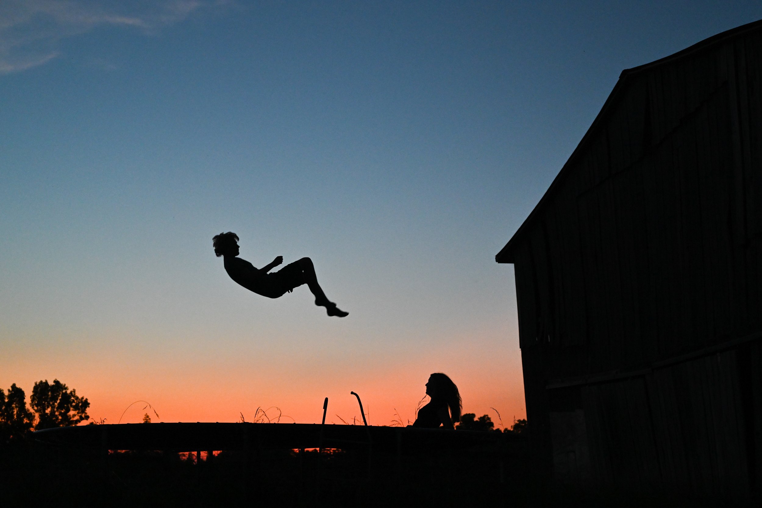 Henry Haag and his girlfriend Brooklyn bounce on a trampoline as the sun sets on Wendell Haag’s farm in Olivet, Kentucky on Sunday, June 16, 2024.