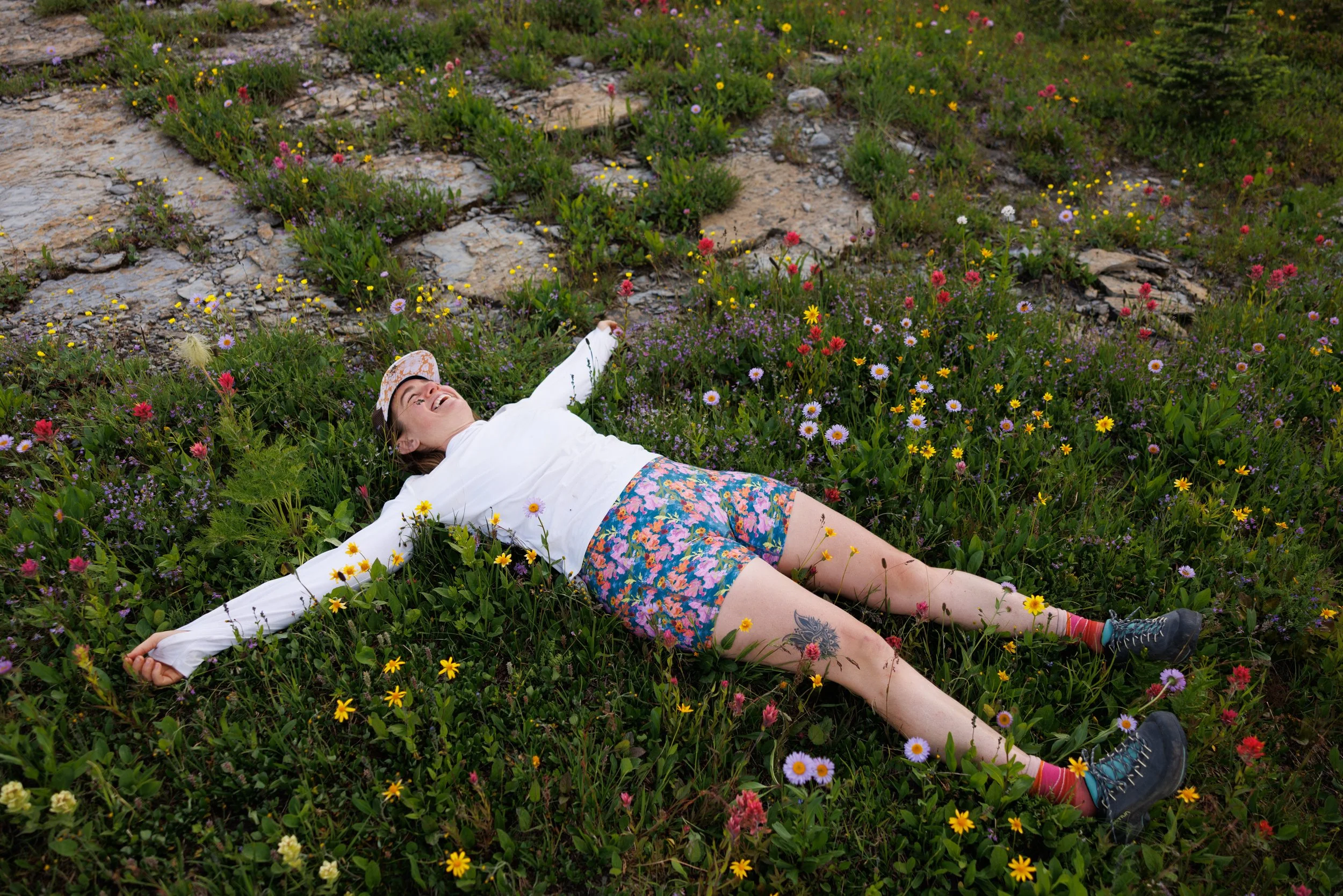 Sarah Straughan giggles in a field of alpine wildflowers deep in the backcountry of Glacier National Park on July 28, 2025. Many of the namesake glaciers in the national park are disappearing due to climate change. 