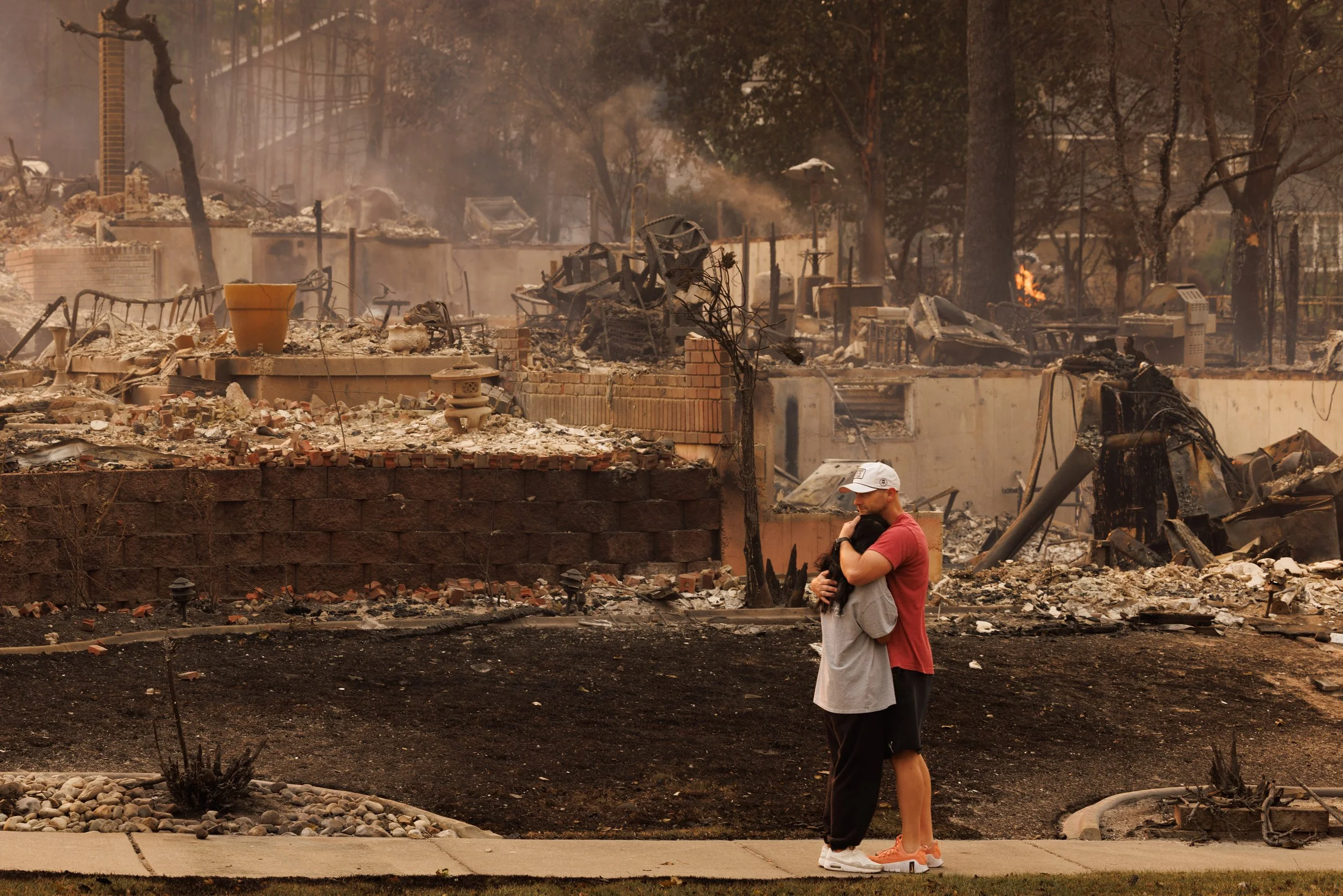 Brian and Christine Farris hug after all of their belongings burned from the Old Trail wildfire in Spokane, Wash. on Sunday, August 2, 2026. The 3,500 acre wildfire, started by a suspected arsonist, was propelled into the city by extreme red flag con