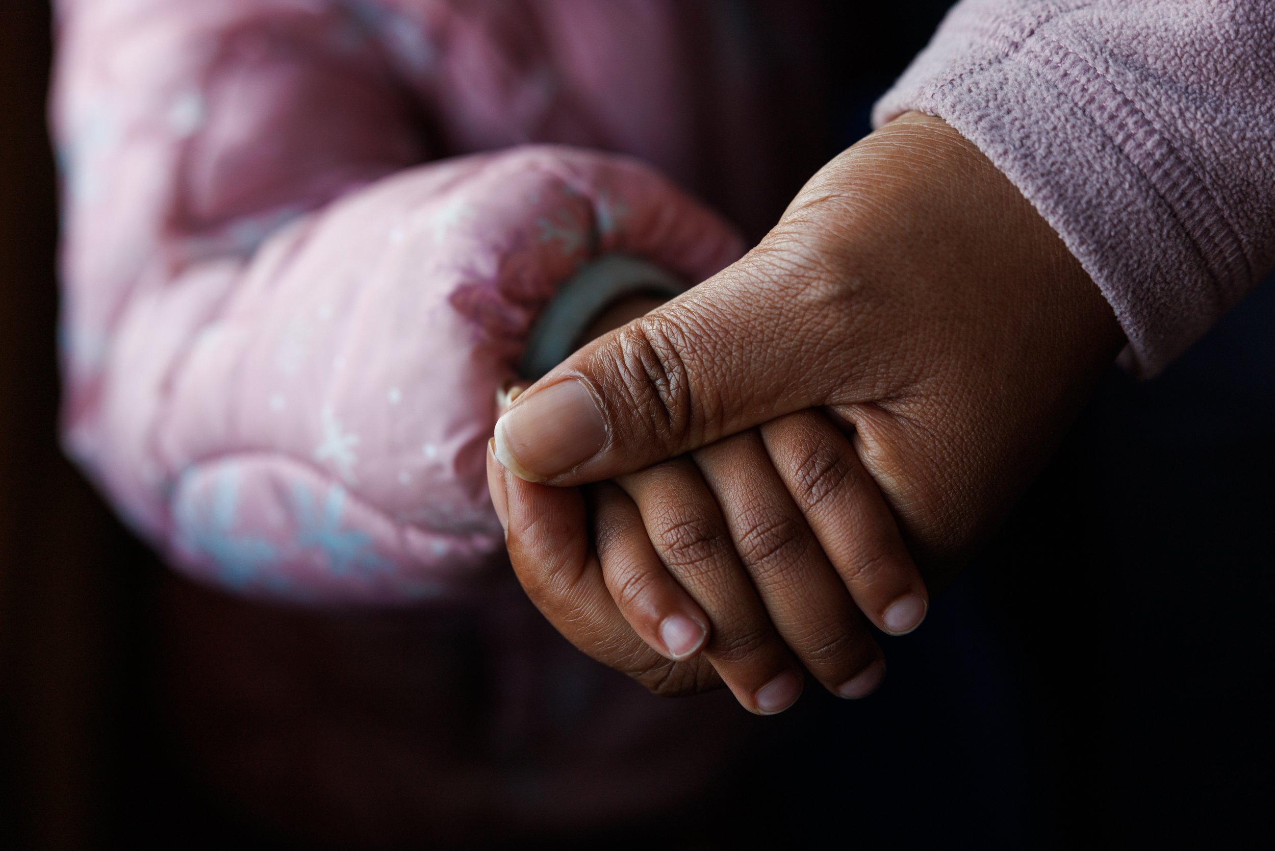 An anonymous U.S. citizen, who arrived as a refugee, holds her daughter's hand and  on Thursday, November 20, 2025. Even with U.S. citizenship, she feels fear as a refugee and a member of the resettlement community. 