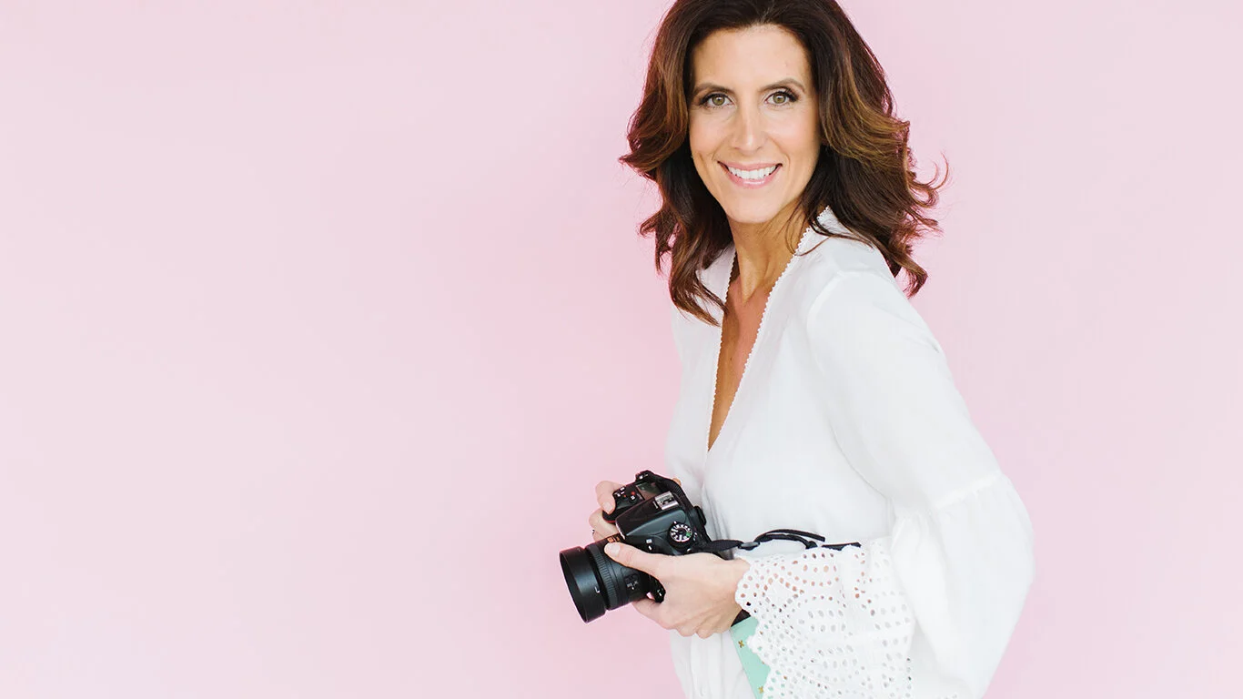 pleasanton-california-photographer-standing-in-front-of-pink-seamless-paper-backdrop-holding-nikon-dslr-camera.jpg