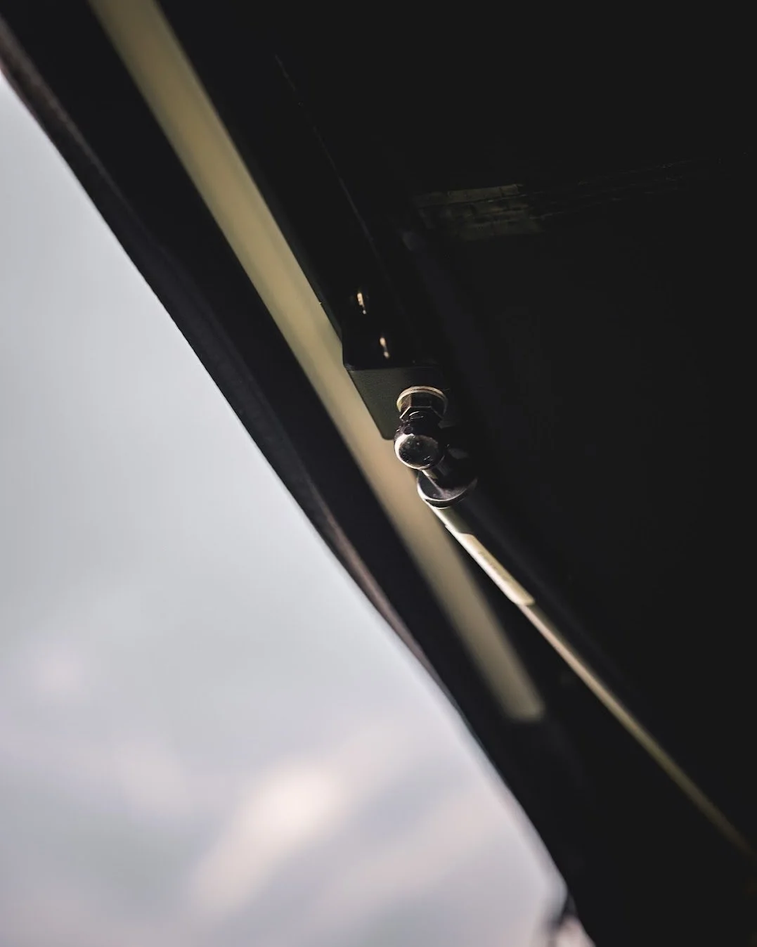 Close-up van een apparaat met een schroevendraaier en knoppen, onder een donkere hemel met wolken.