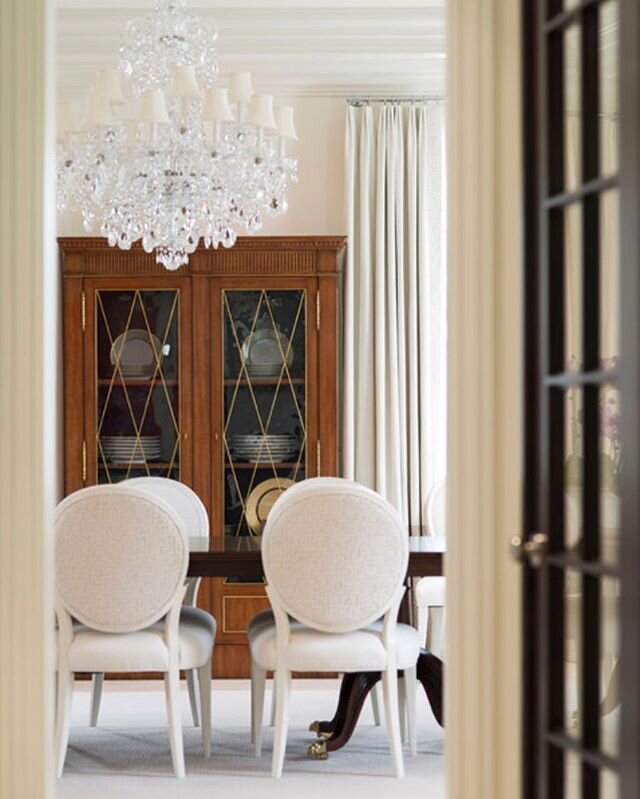Contrasting elements of white, wood &amp; crystal add drama to this dining room.