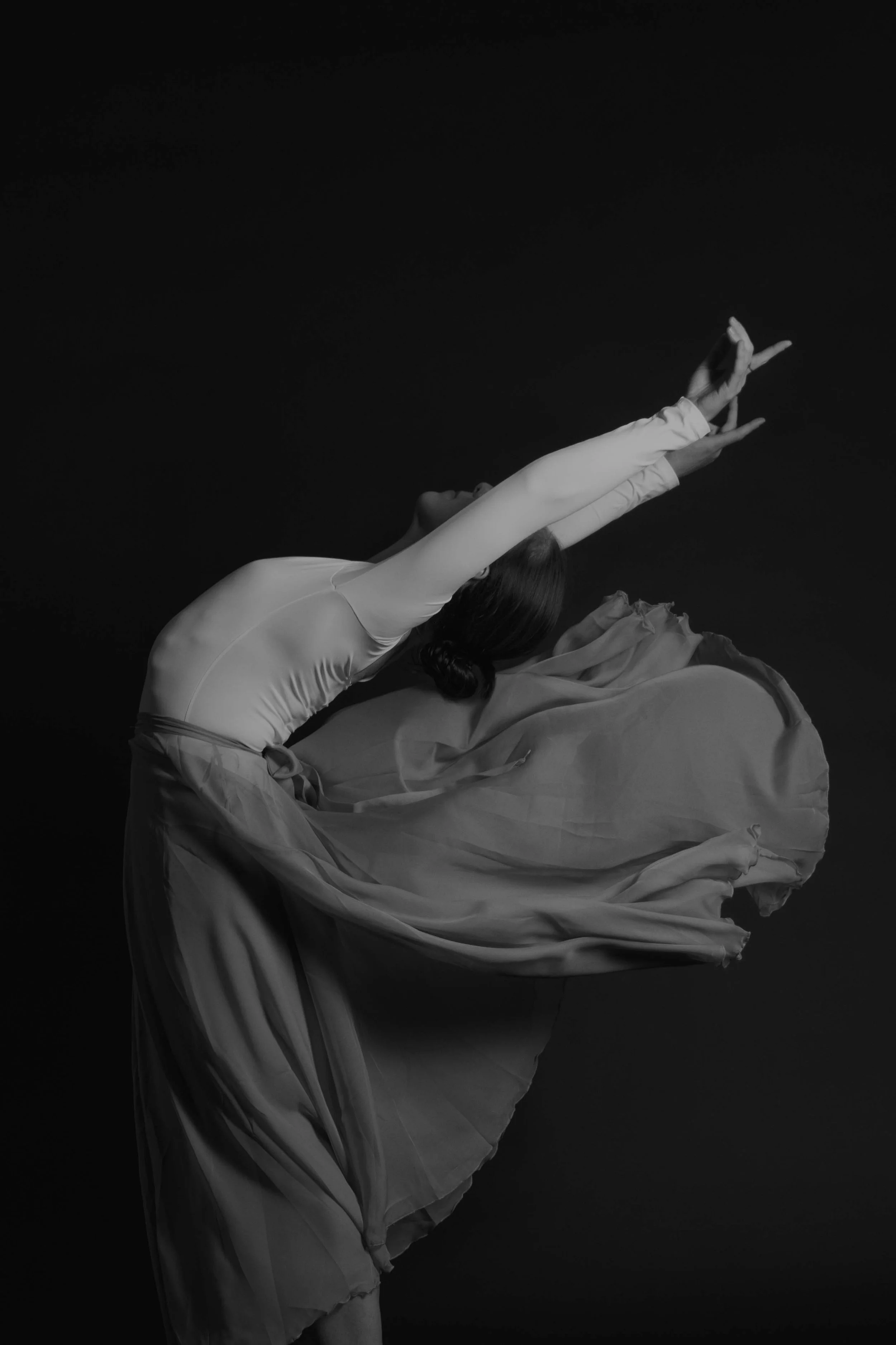 Dancer at full extension with a dramatic costume in a studio setting