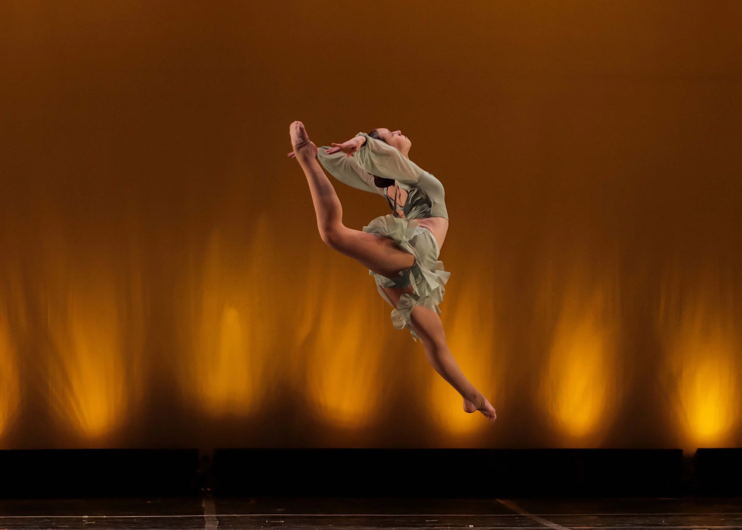 Dancer captured mid-performance with dramatic lighting and full extension