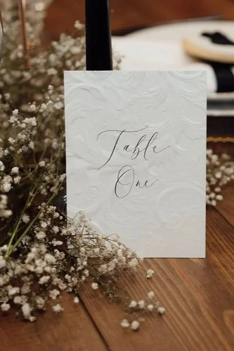 Elegant wedding table signs with handwritten details and candlelight